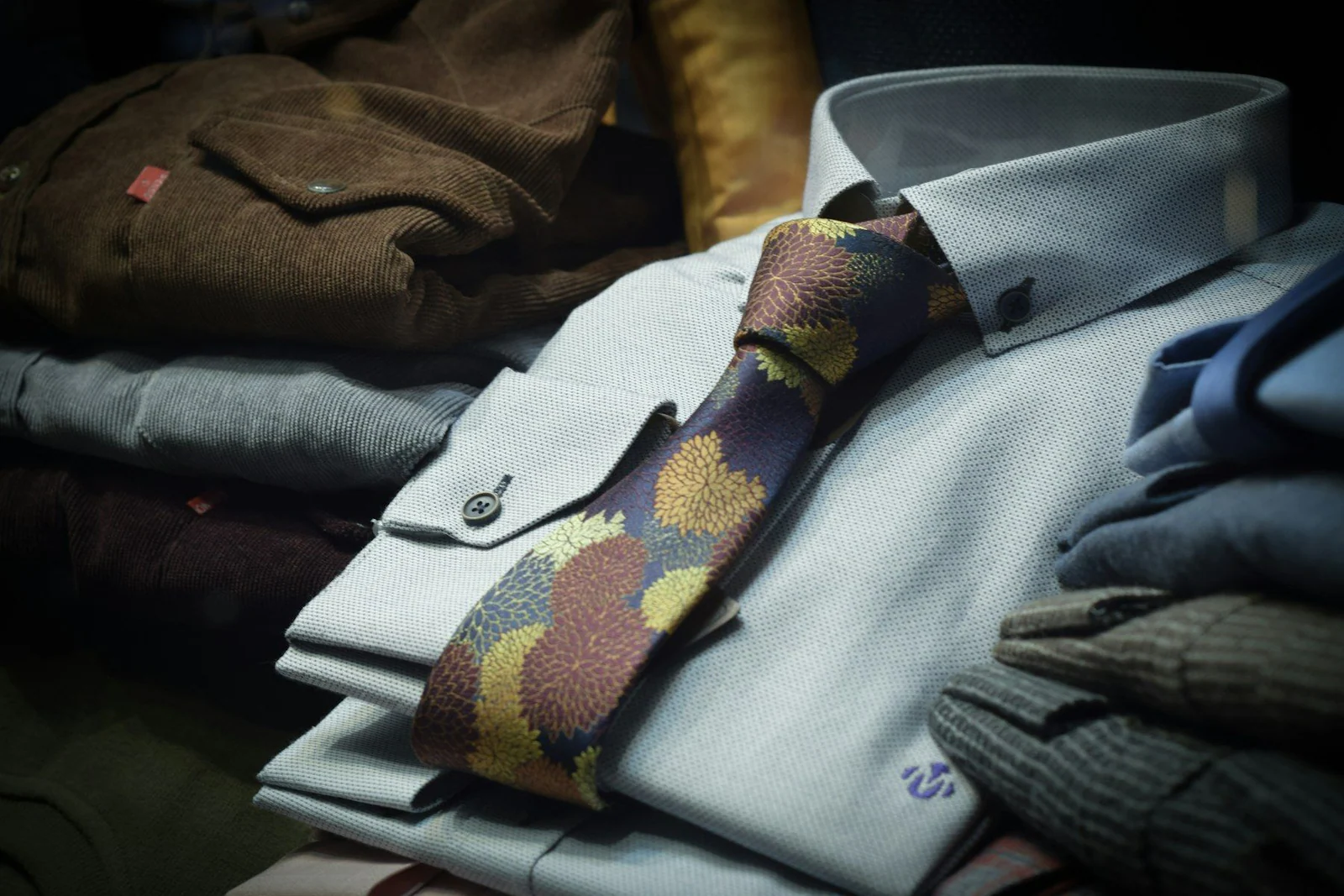 A tie sitting on top of a pile of clothes
