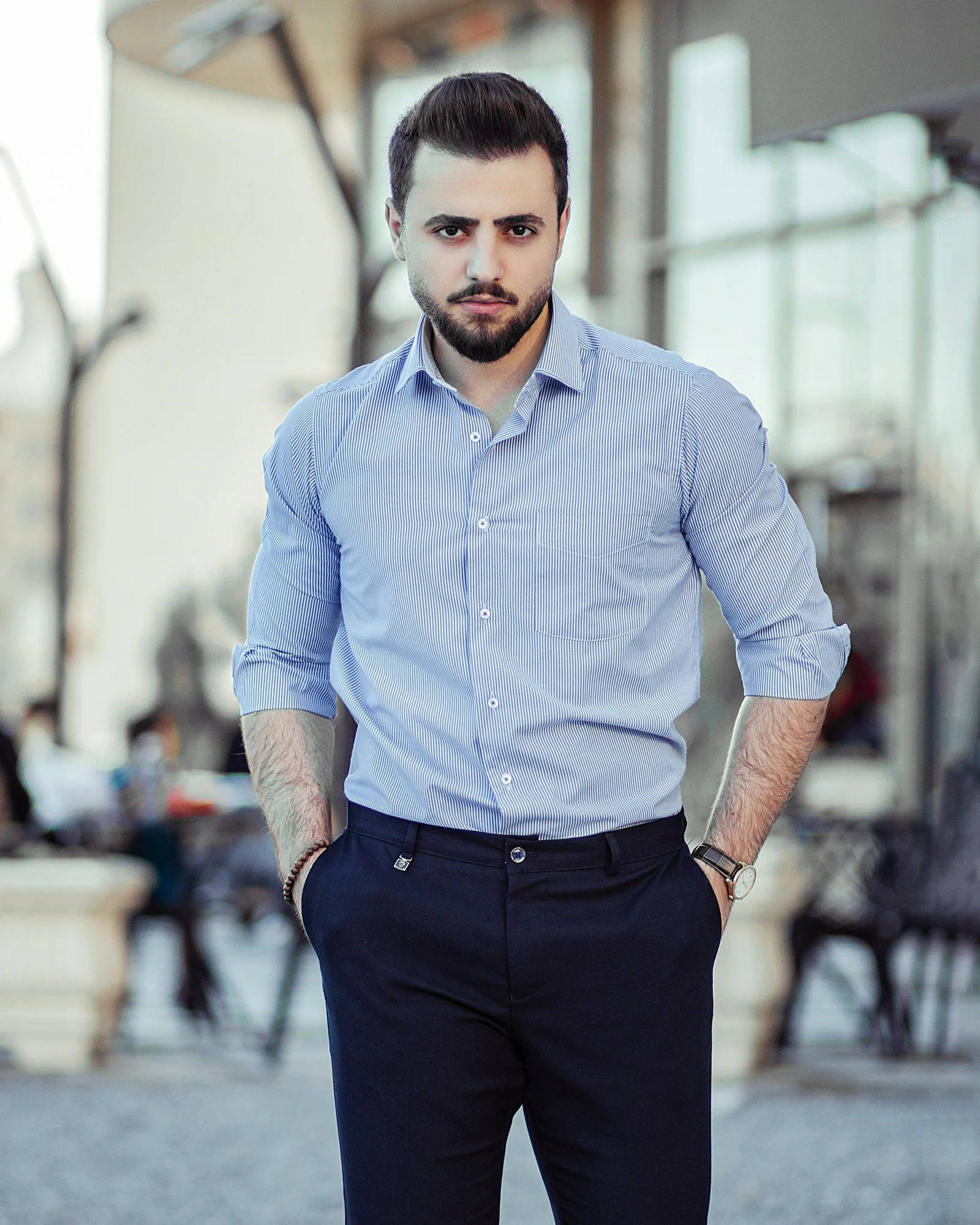 Man in blue dress shirt and black dress pants standing