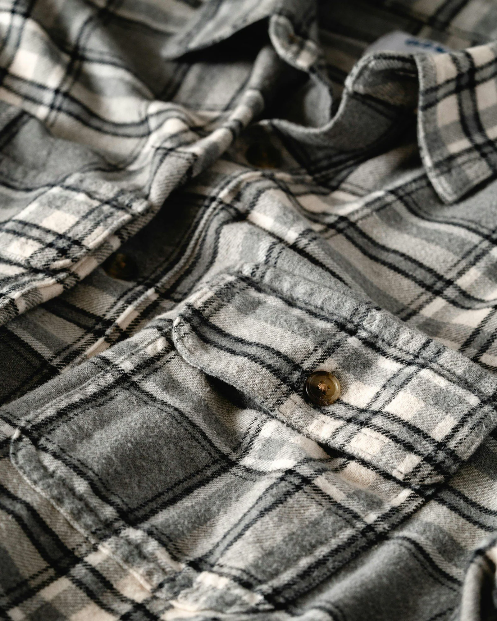 Grey and white plaid flannel shirt with a buttoned pocket