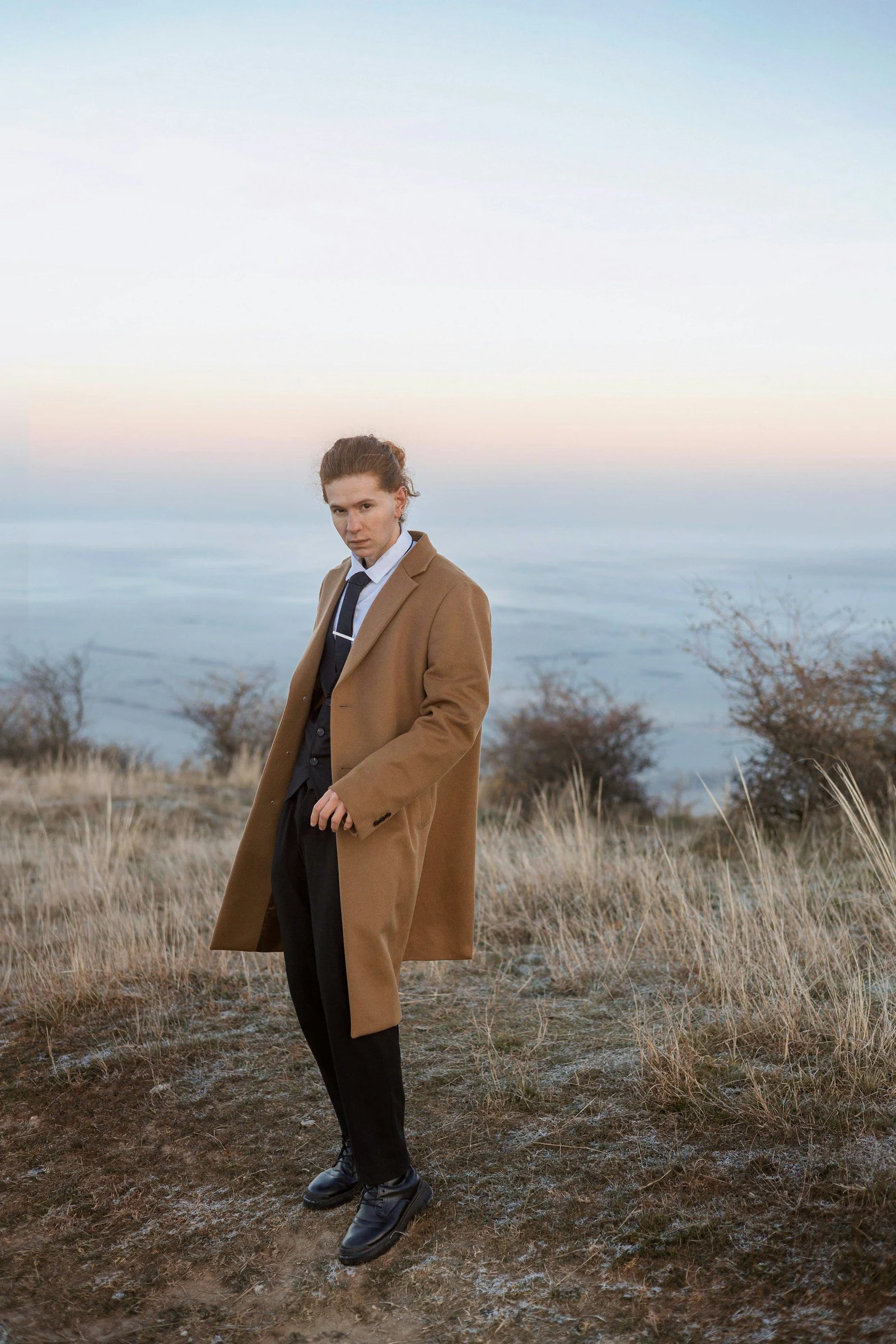 A man in a coat and tie standing on a hill