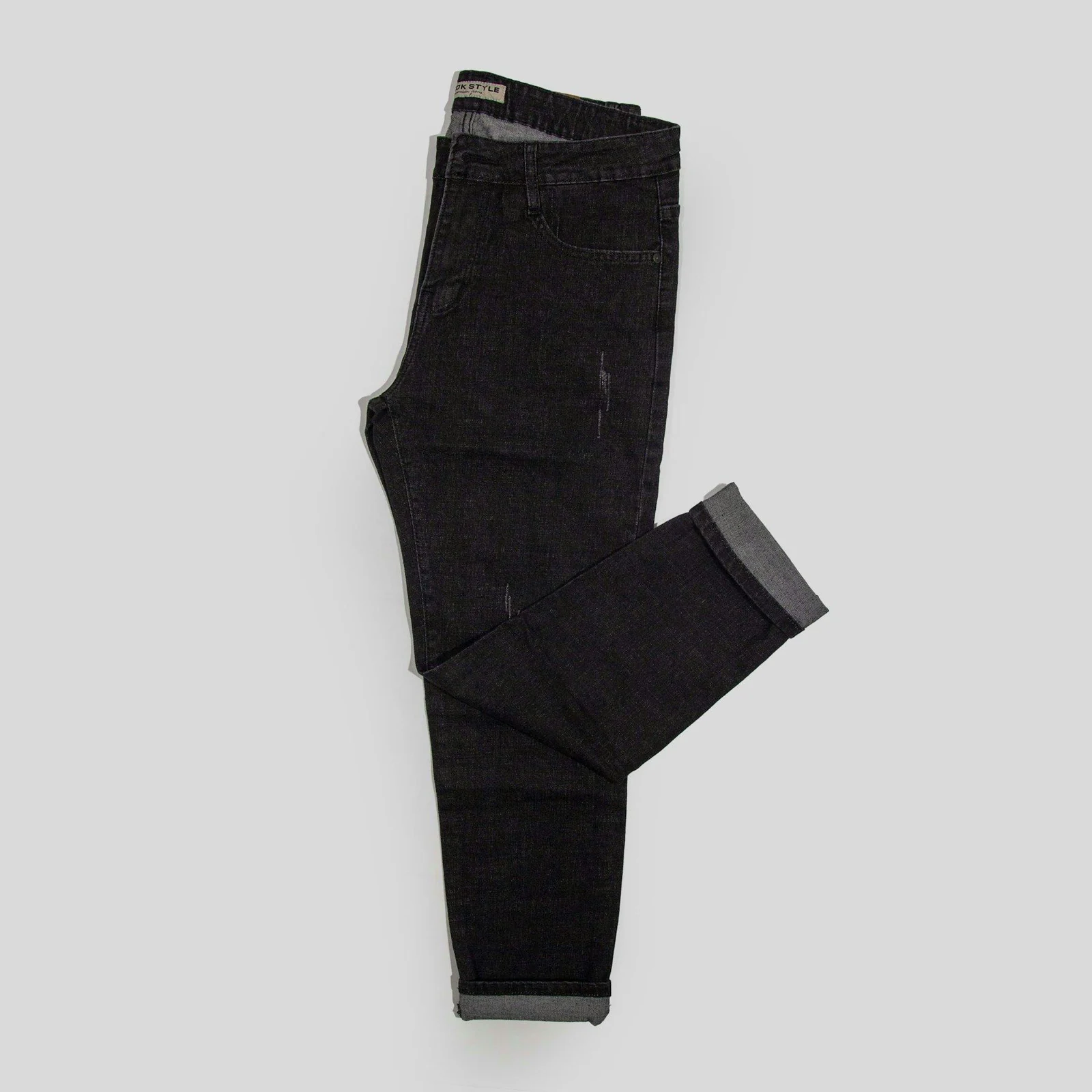 A pair of black jeans sitting on top of a white floor