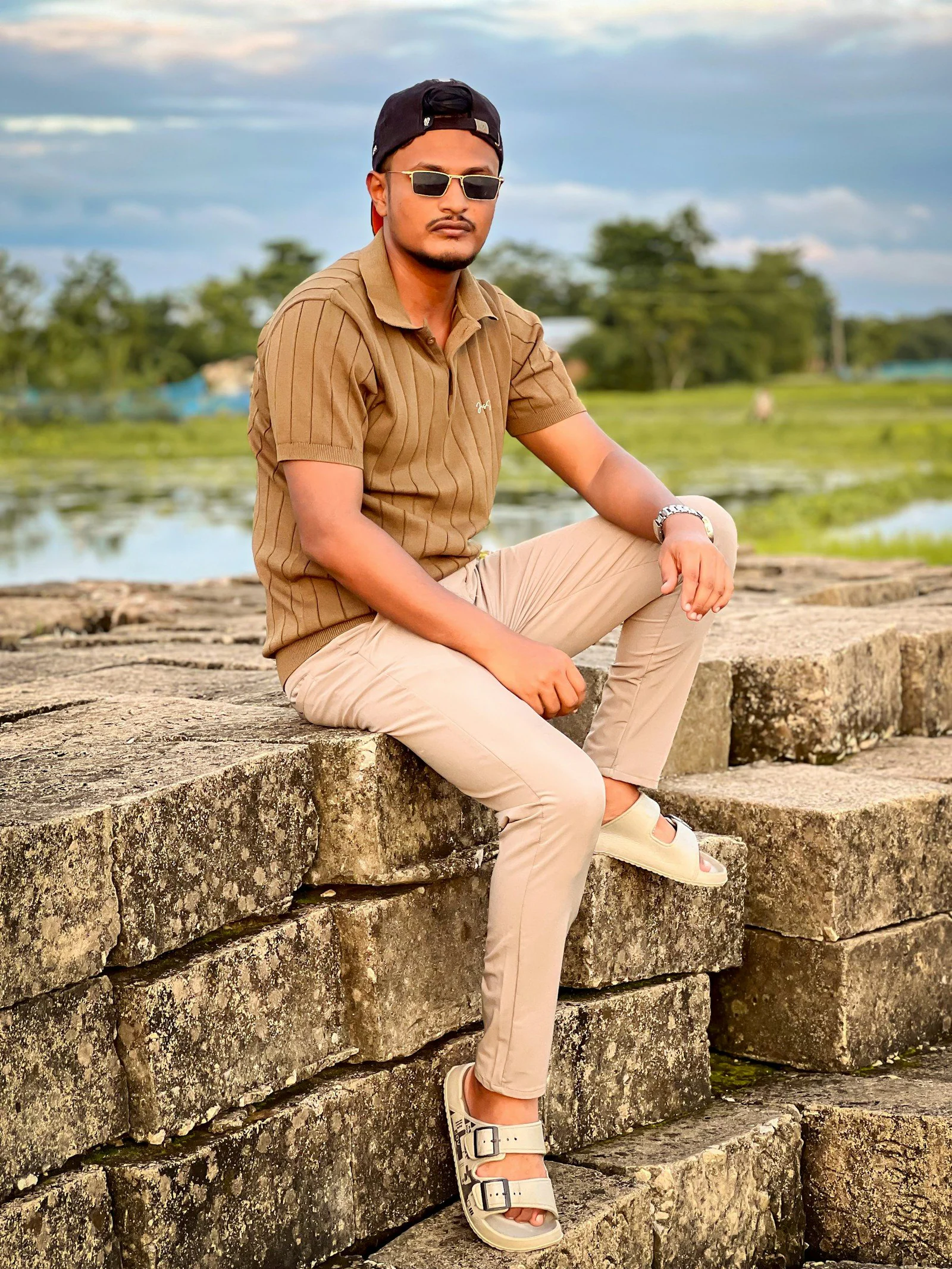 Man in brown polo on stone