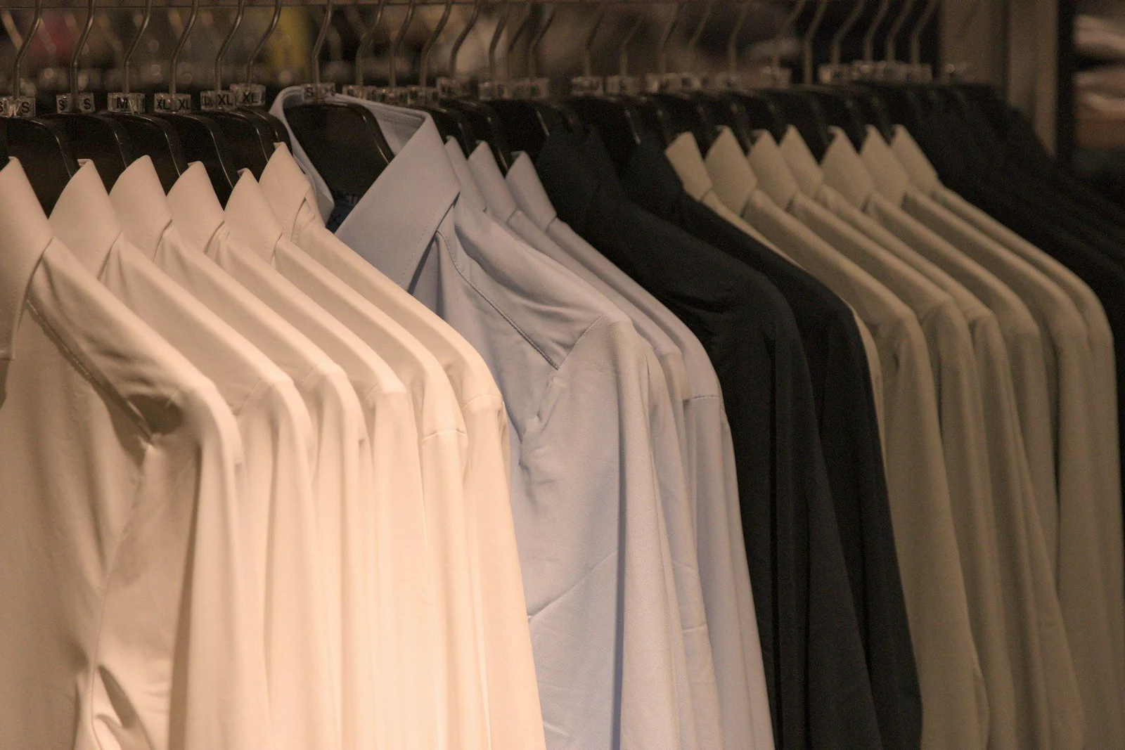 Shirts of various colors hang on hangers