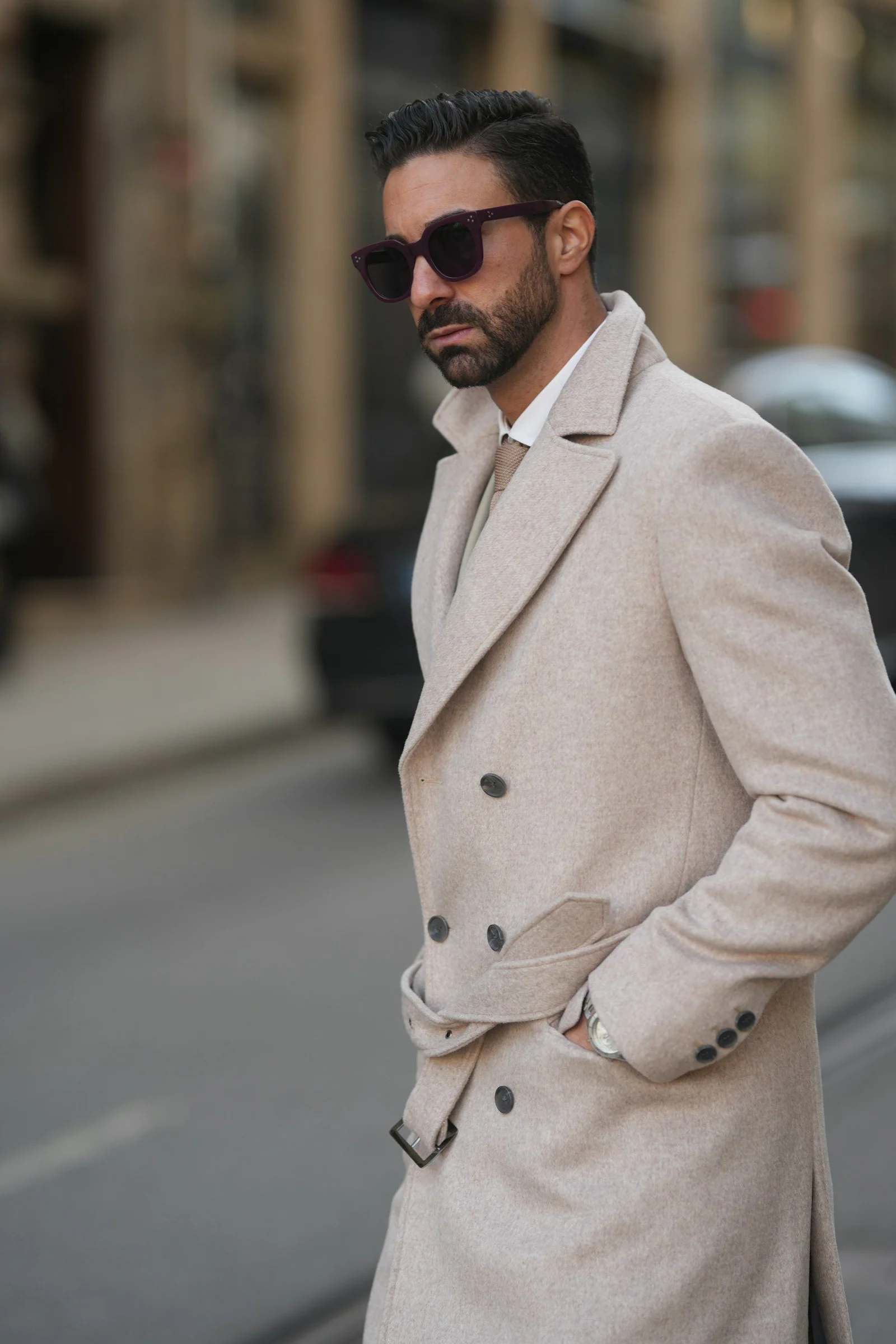 A man in a trench coat is standing on the street