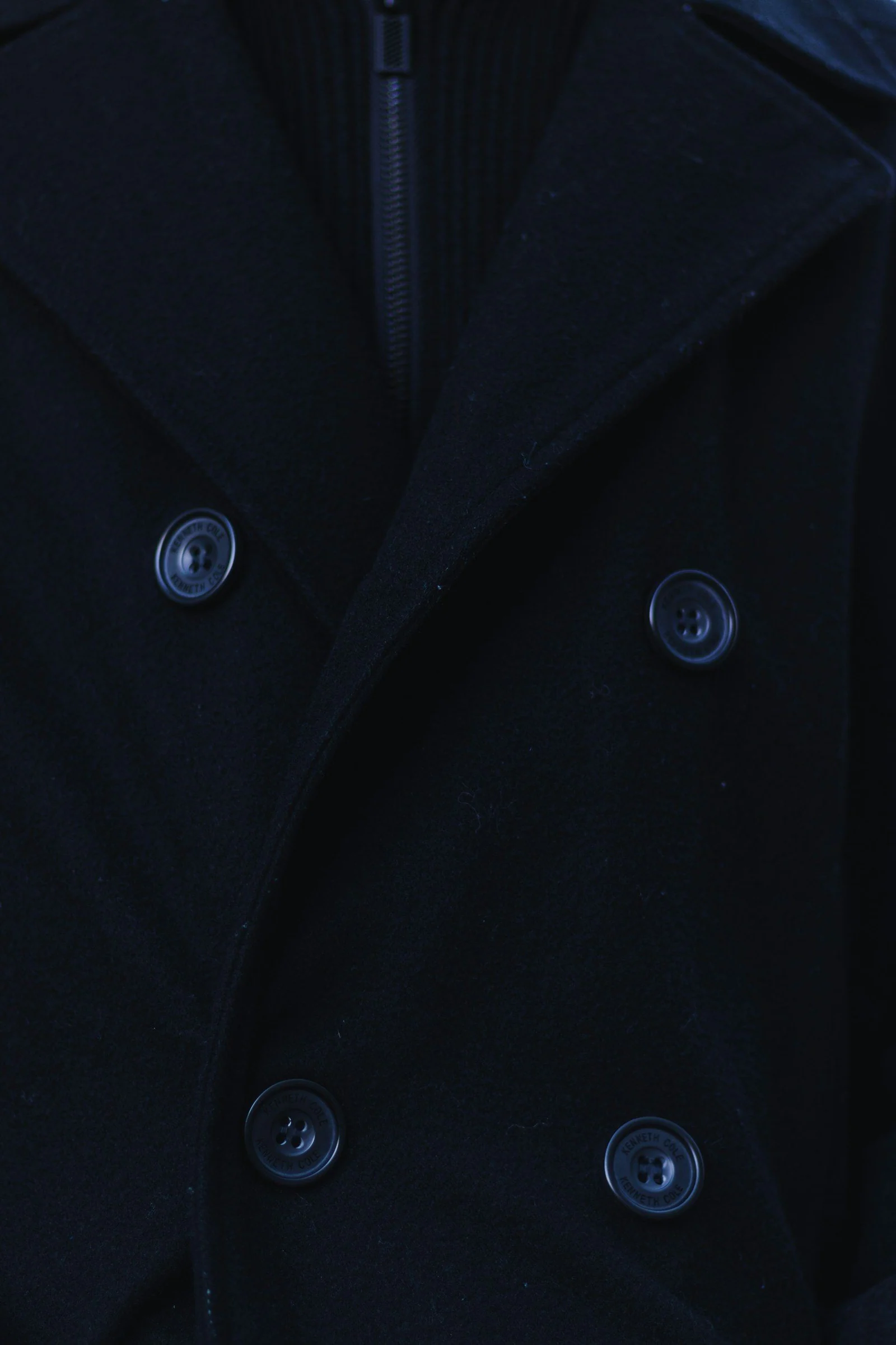 A man wearing a black peacoat and a black shirt