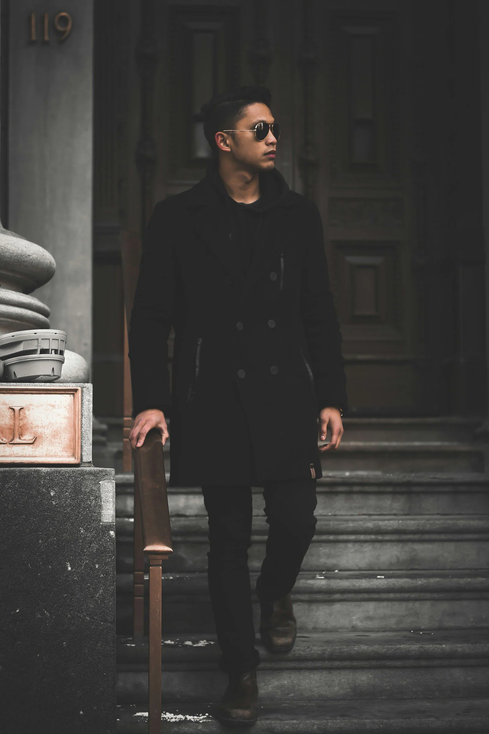 Man in black long sleeve shirt and black pants standing on stairs