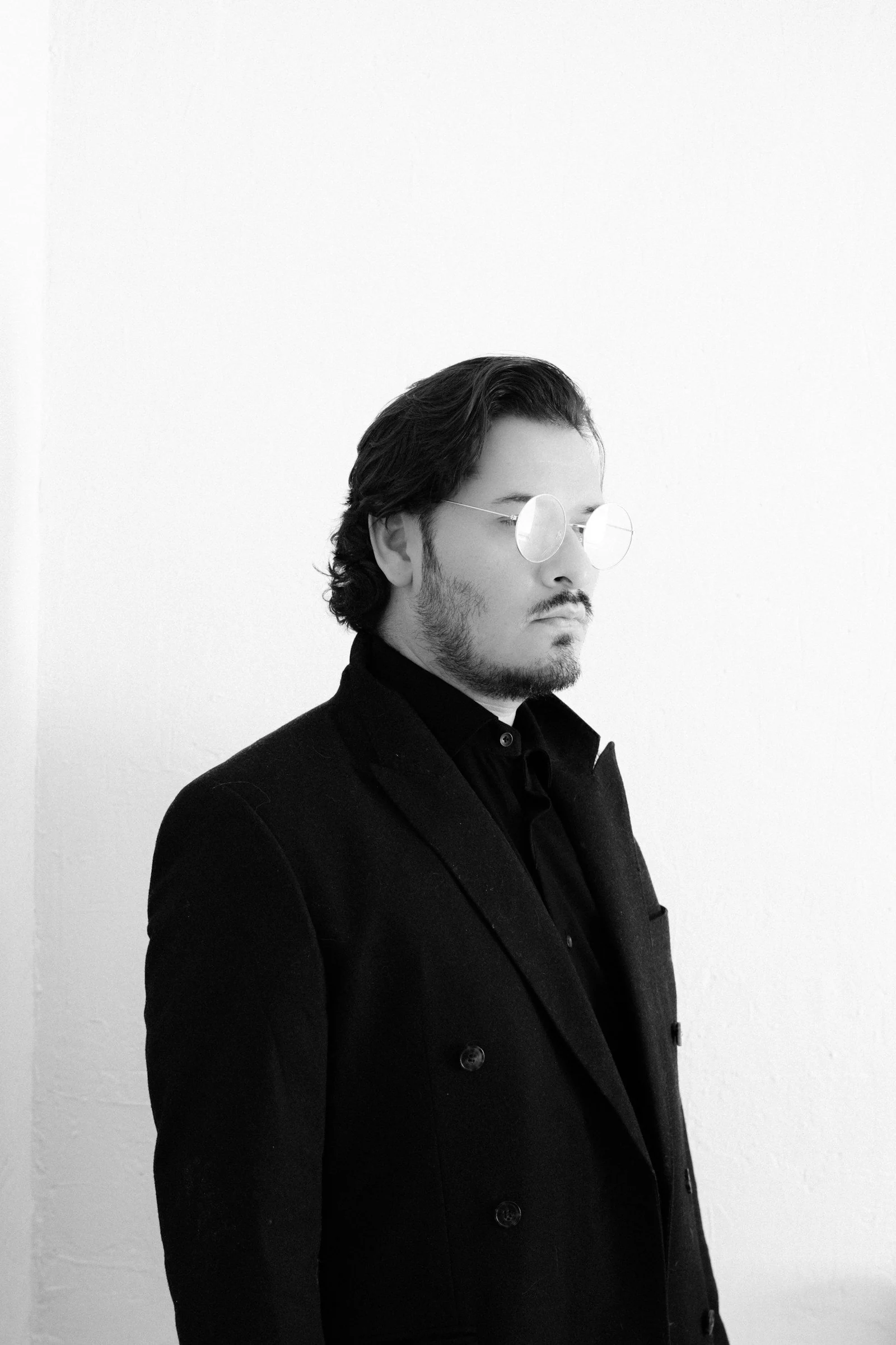 Man in black suit with round glasses