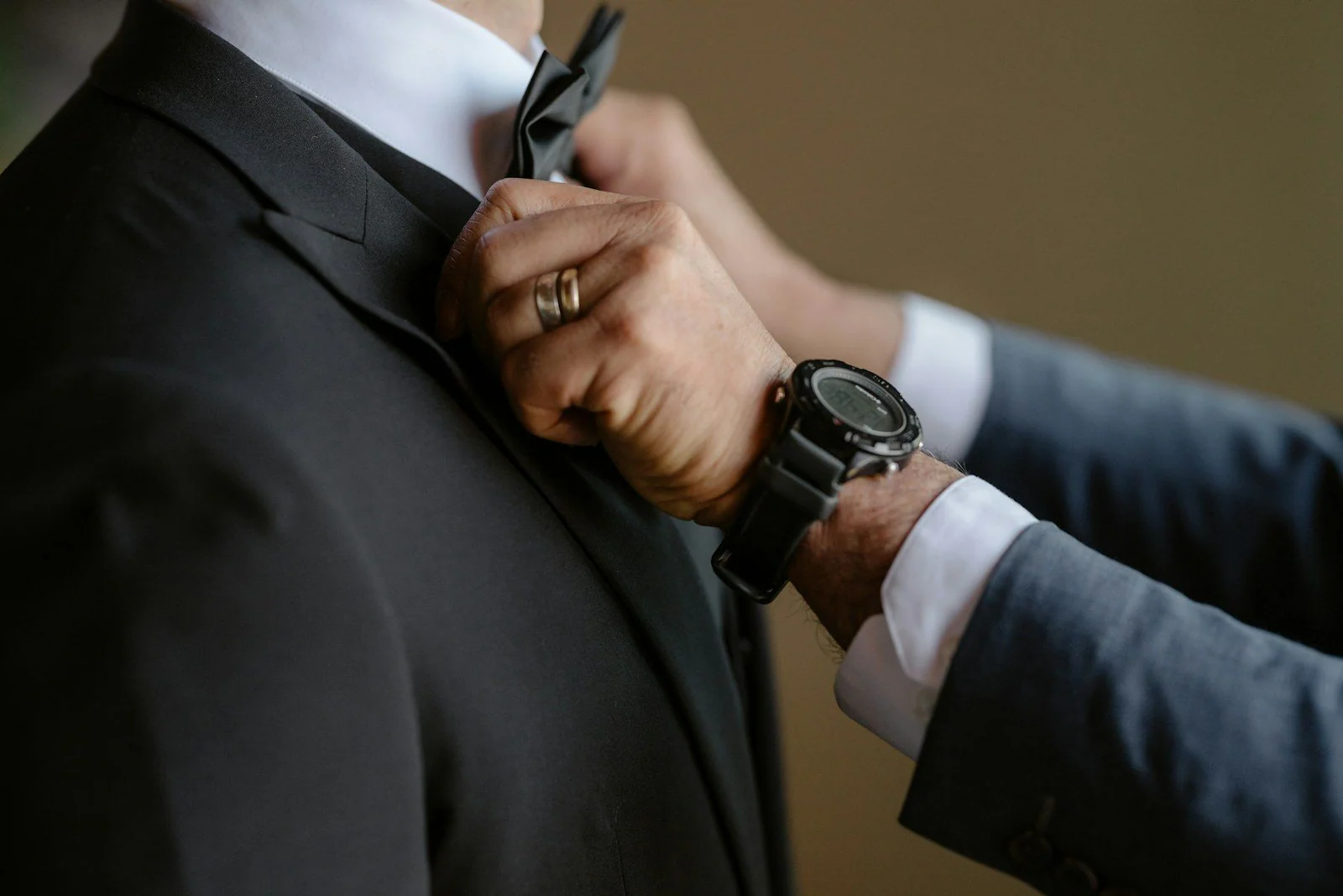 A man adjusts a bow tie on another man