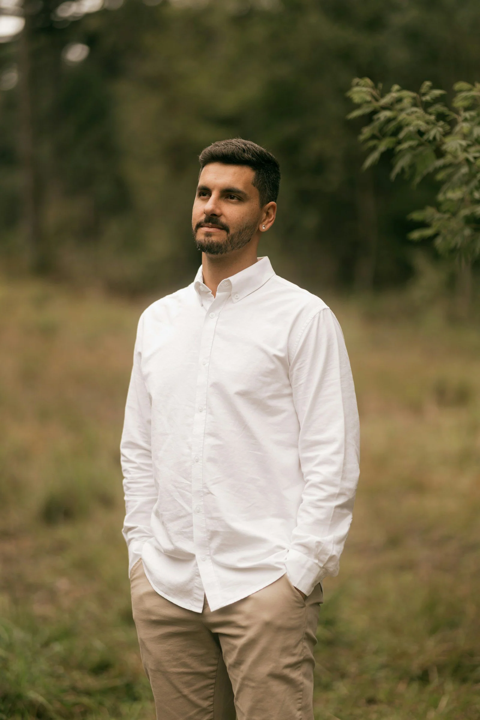 Bearded man in white shirt standing in a grassy field