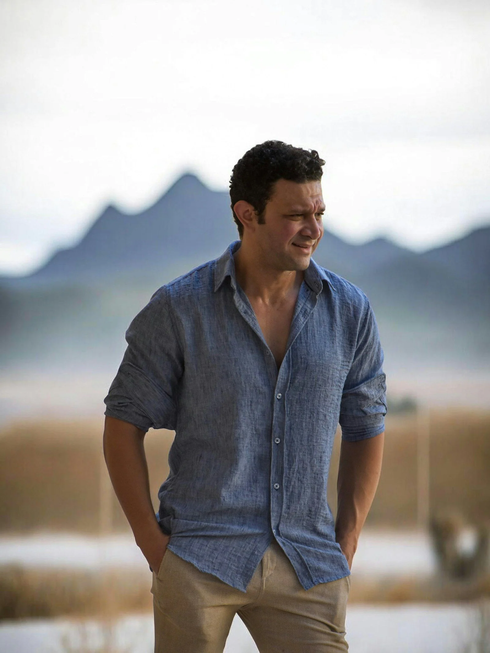 Man in blue shirt outdoors hands in pockets looking right