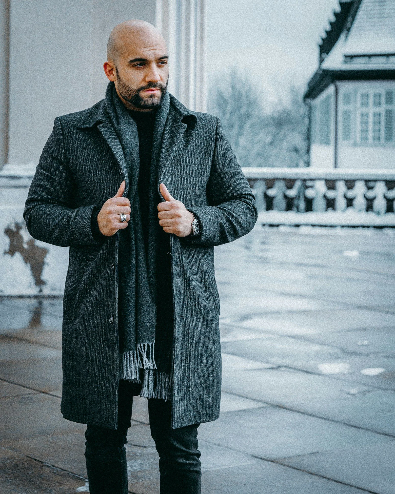 Man in black coat standing on sidewalk during daytime