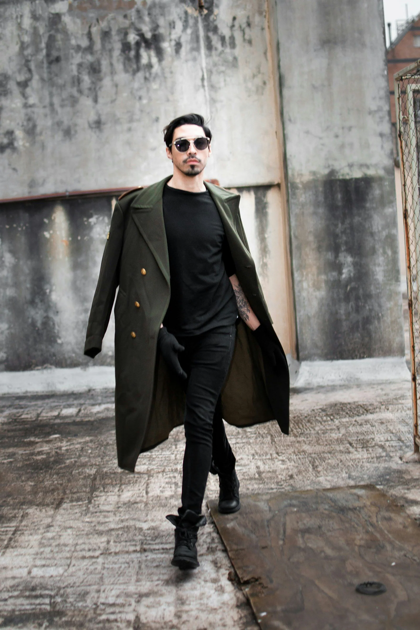 A man walking down a sidewalk wearing a coat