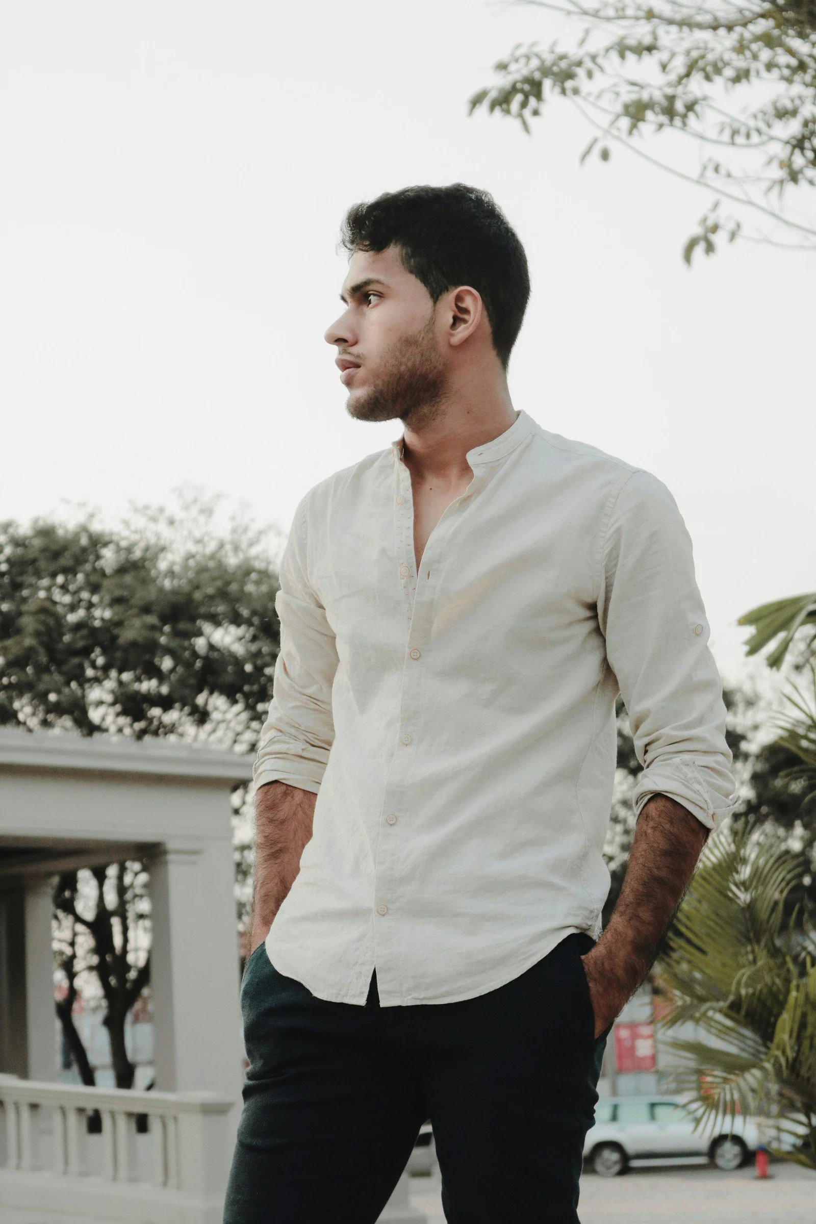 Man in white dress shirt standing near green plants during daytime