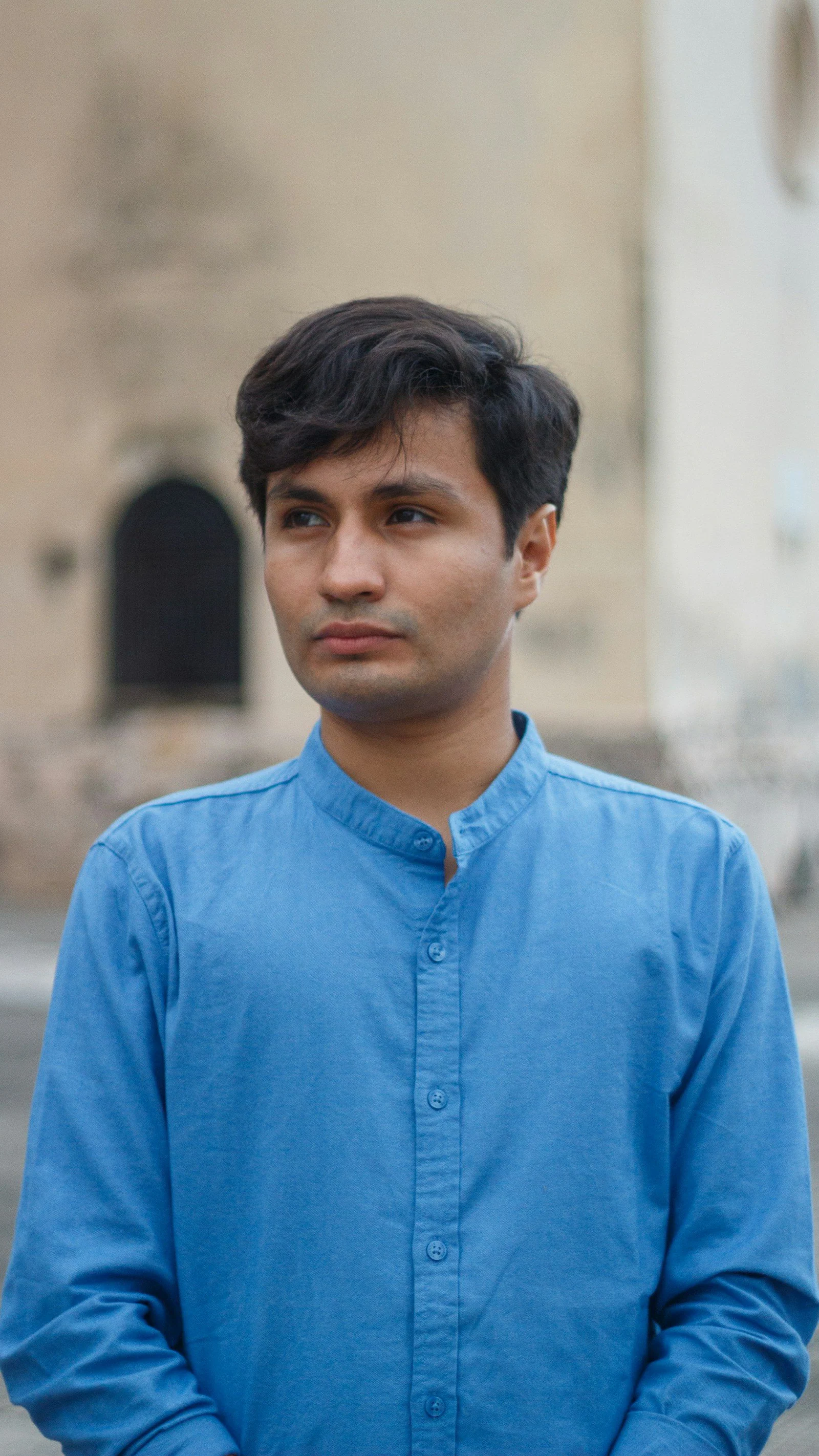 A man in a blue collared shirt stands outdoors