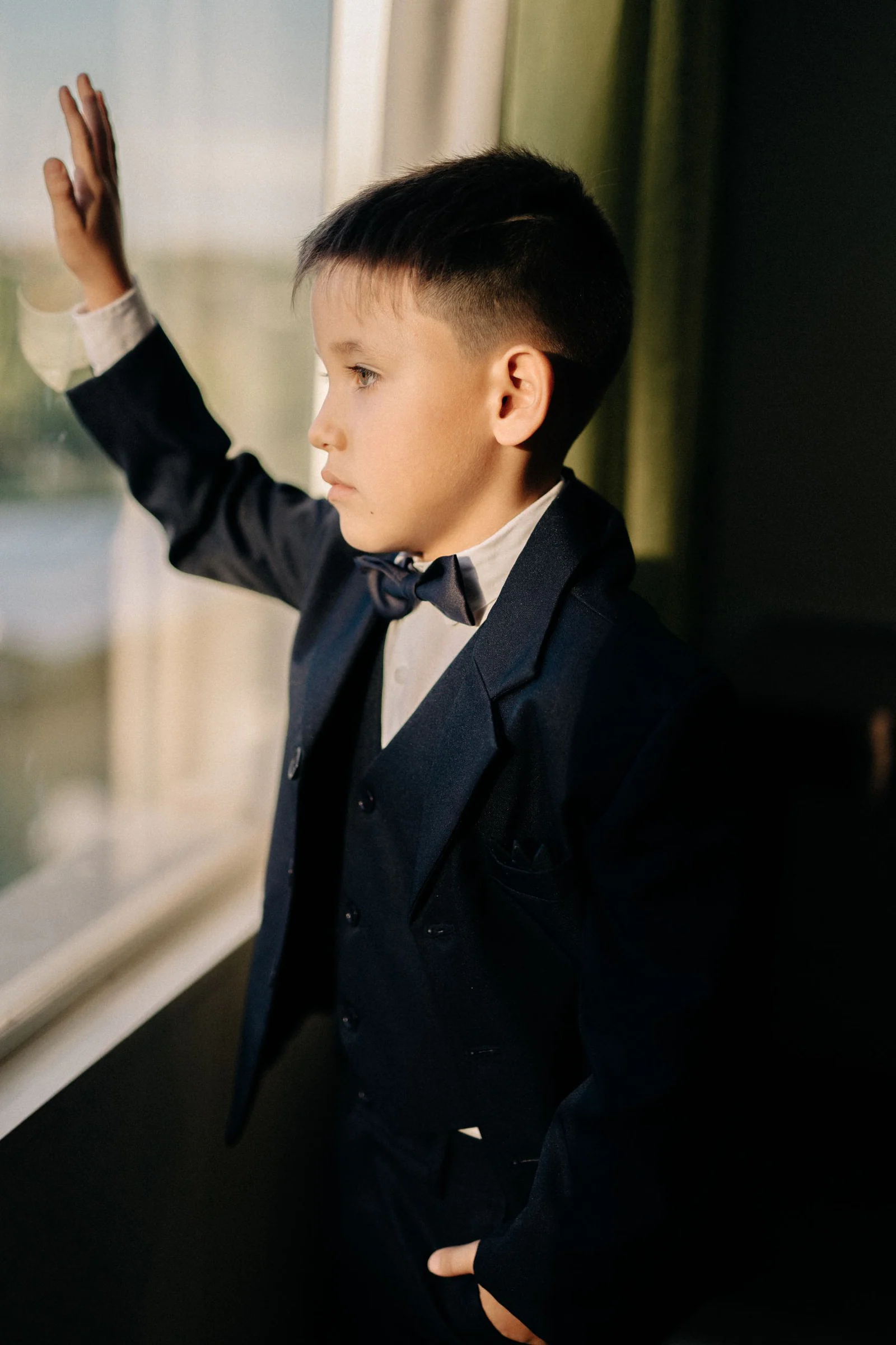 Boy wearing formal suit looking through window