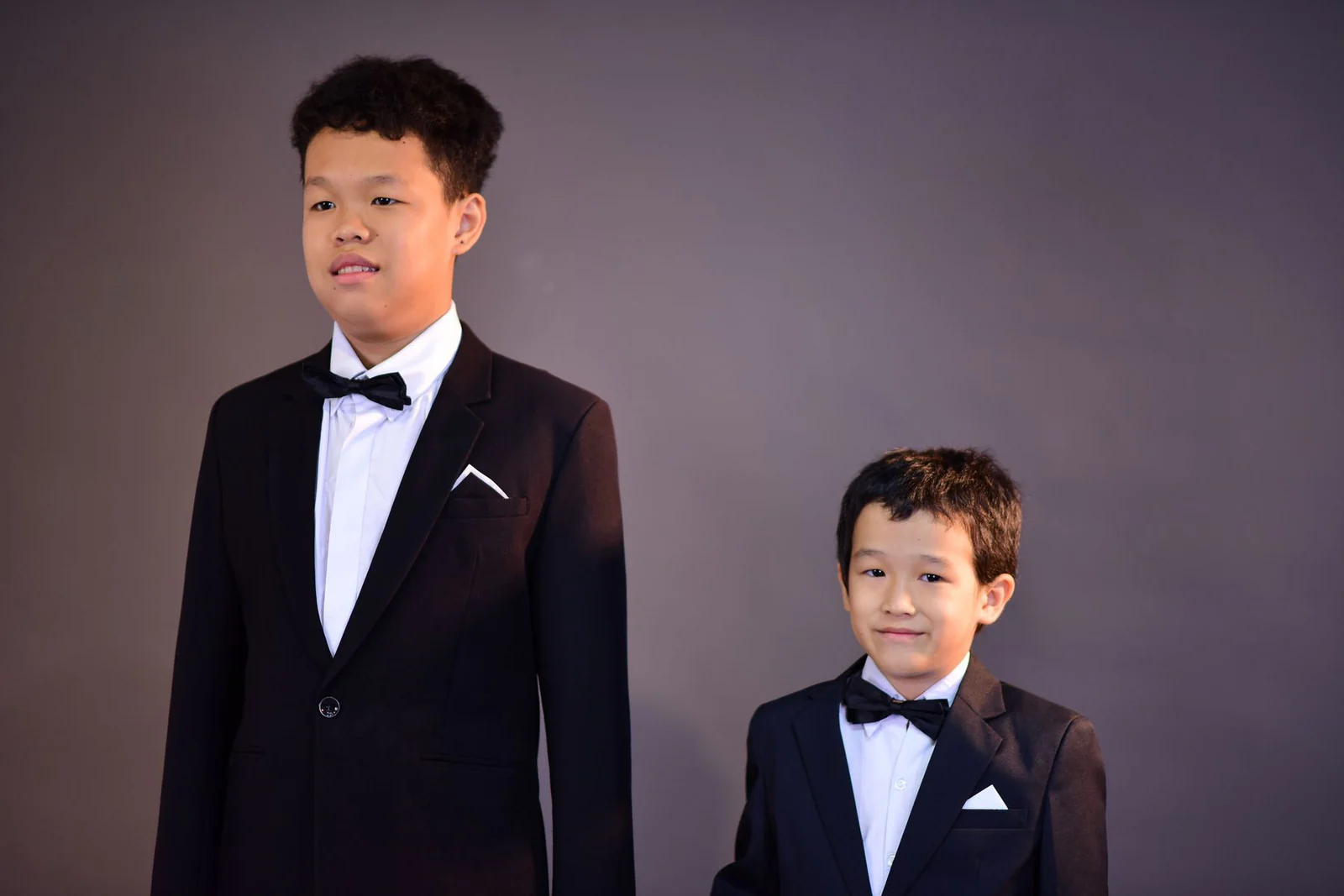 Young boys in formal attire against neutral background