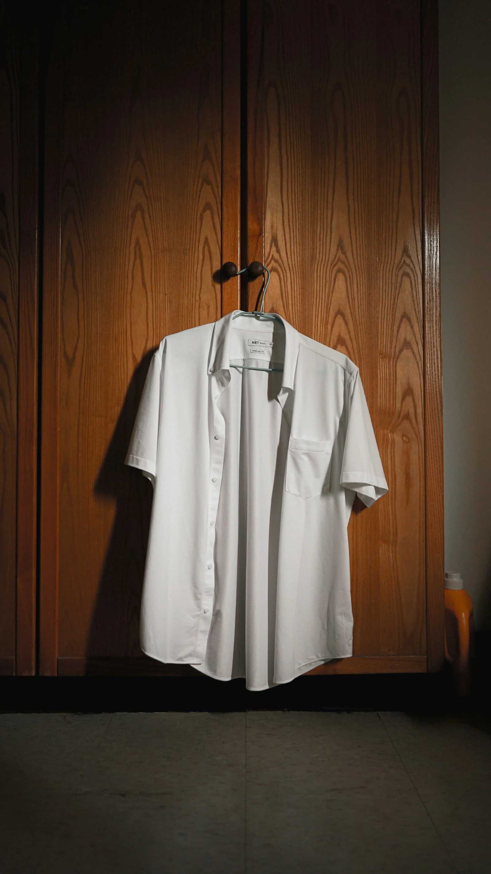 White polo shirt hanged on brown wooden cabinet