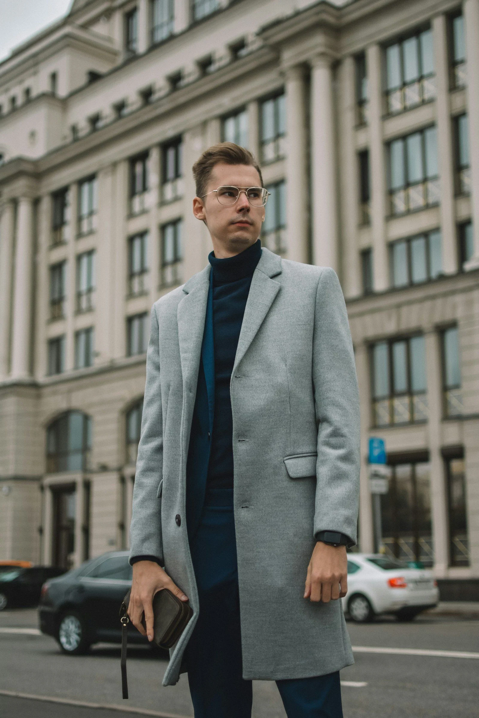 Man in gray suit jacket standing near cars during daytime