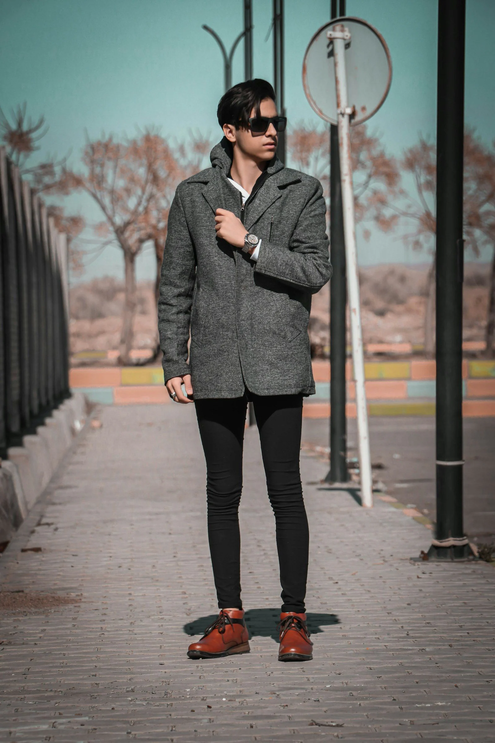 A man standing on a sidewalk next to a pole