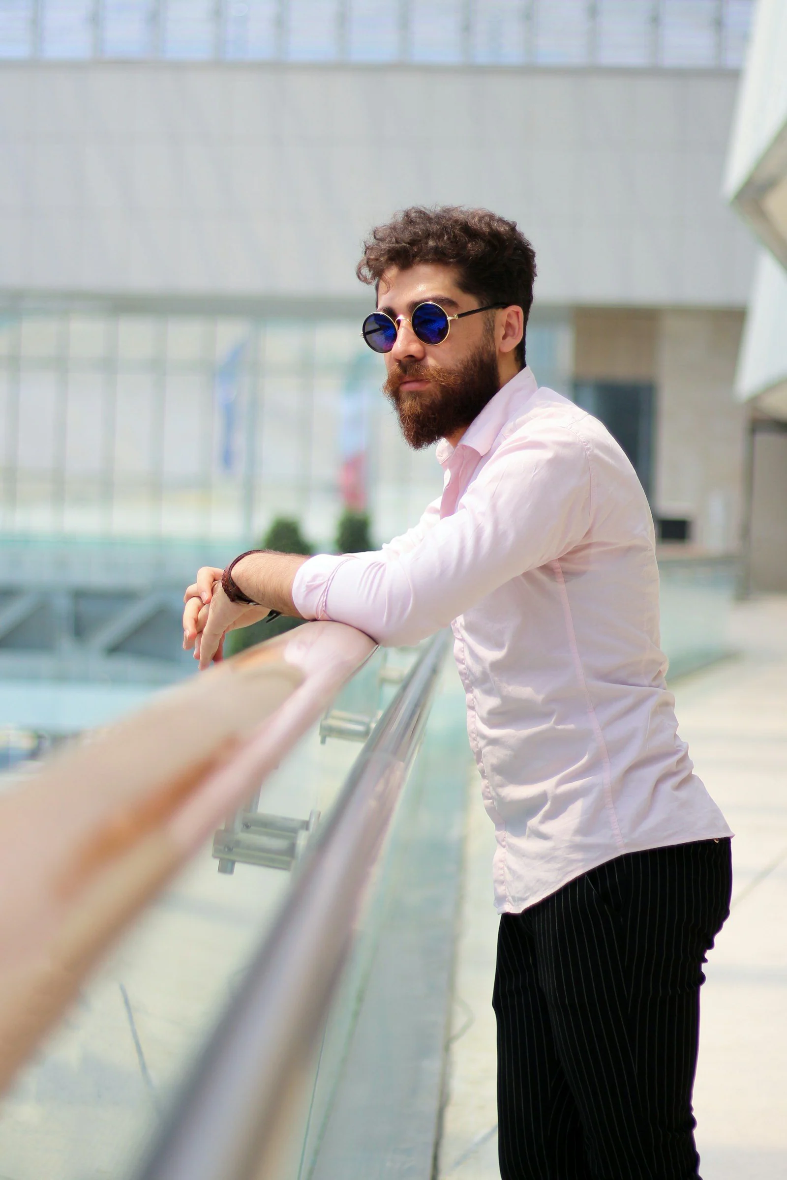Man in white dress shirt and black pants wearing black sunglasses standing on escalator