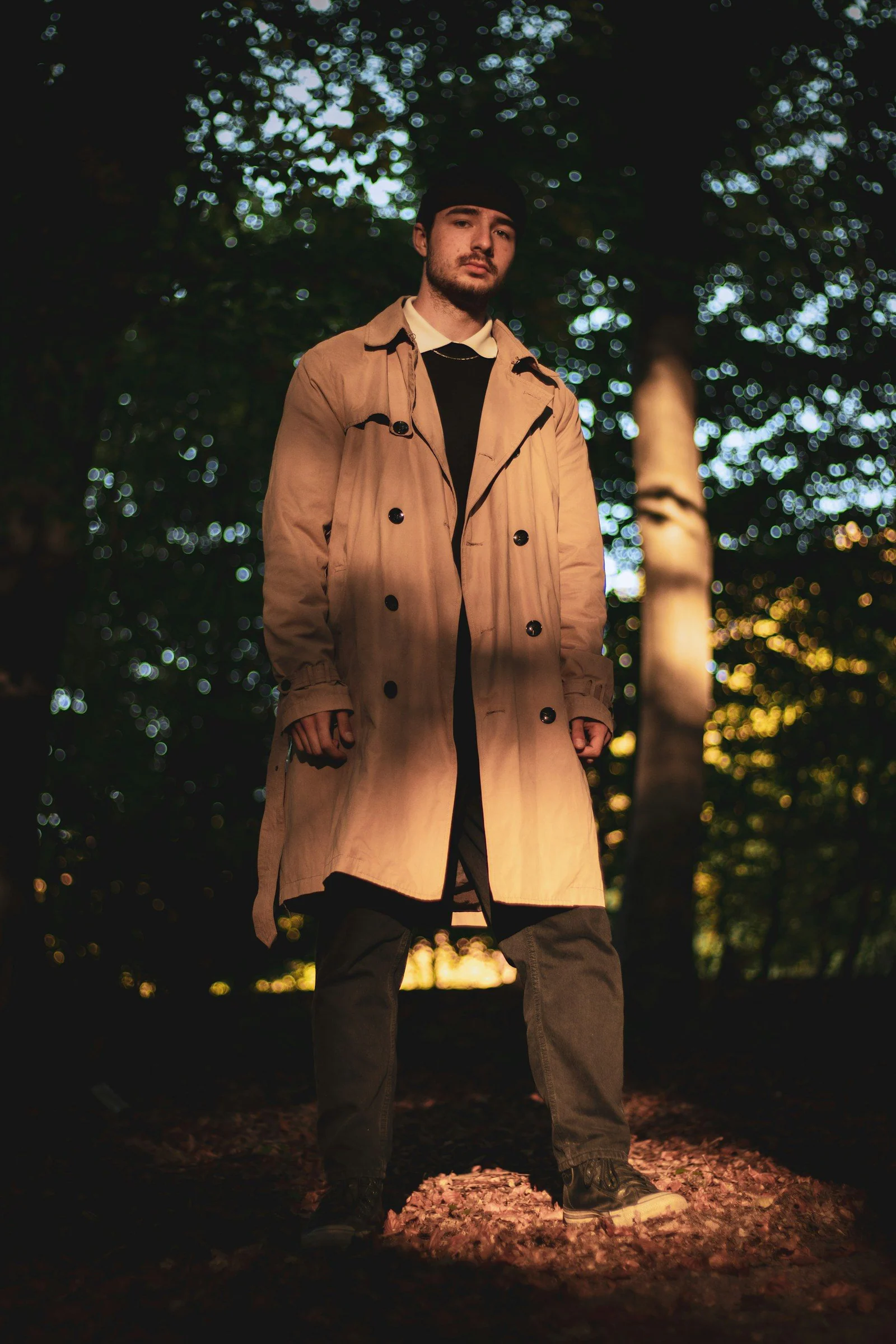 A man in a trench coat standing in the woods