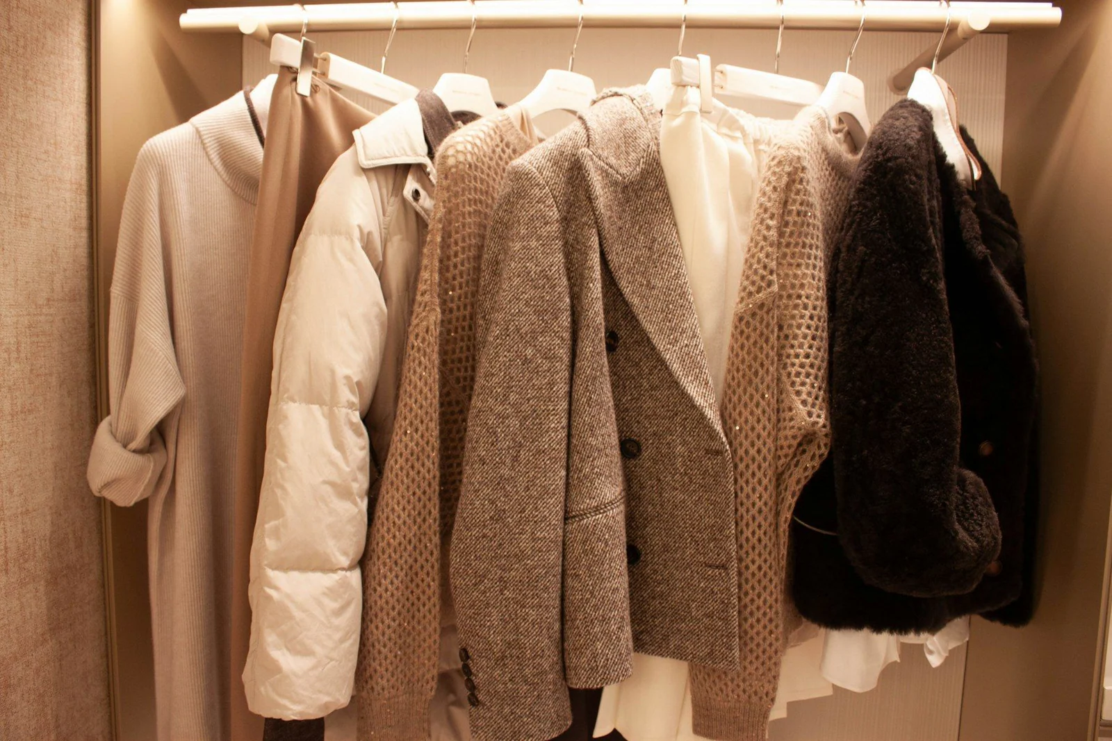 Various coats and jackets hanging on a closet rack