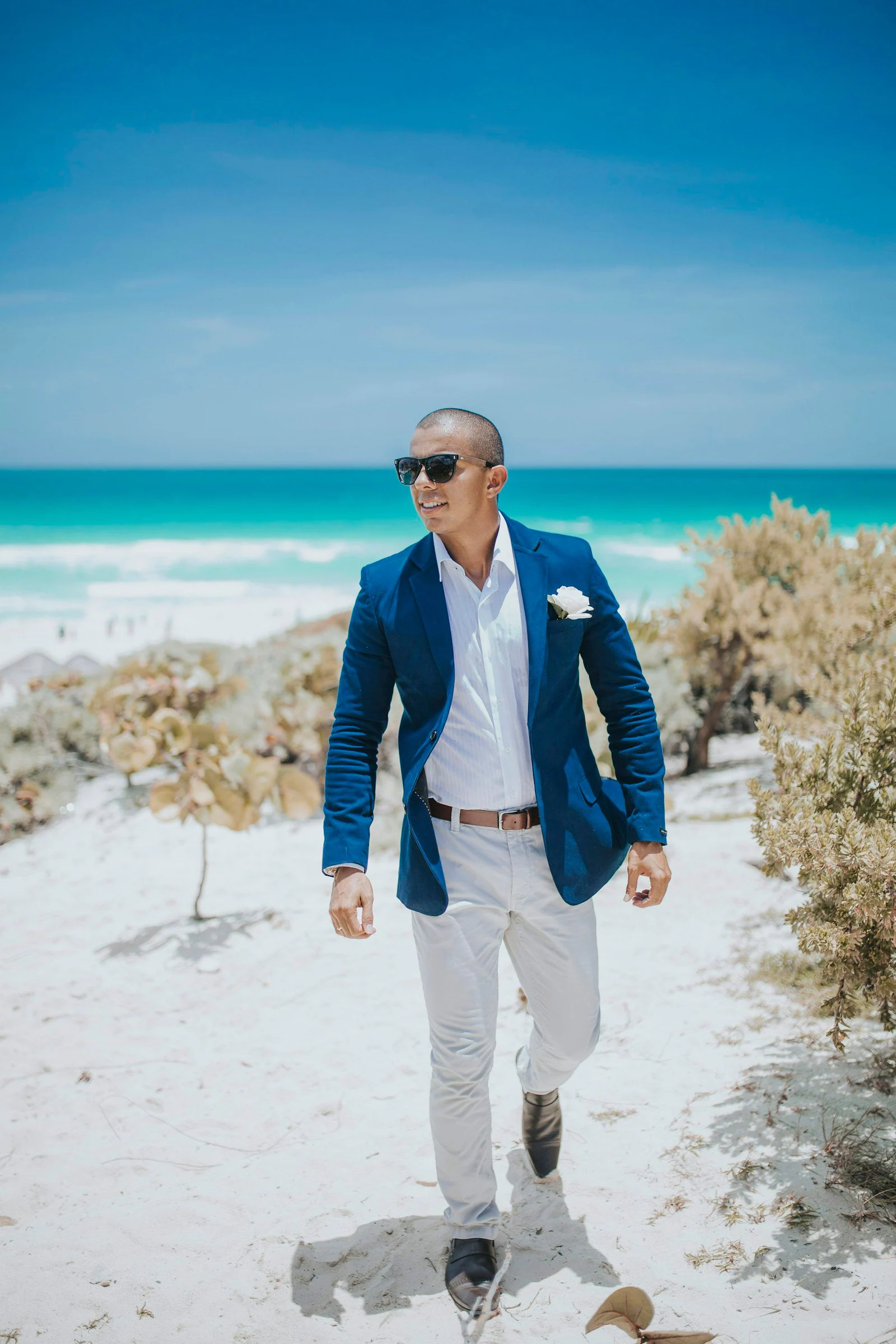 Man in blue suit standing on white sand near body of water during daytime