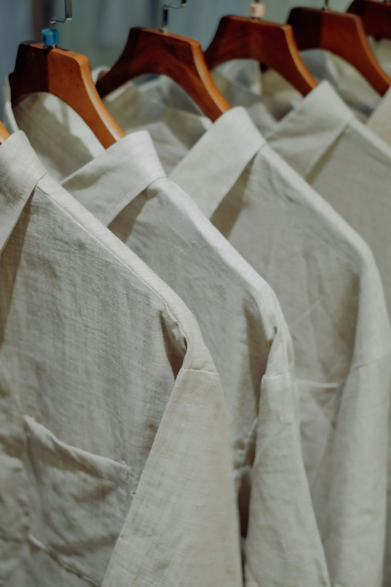 A row of white shirts hanging on wooden hangers