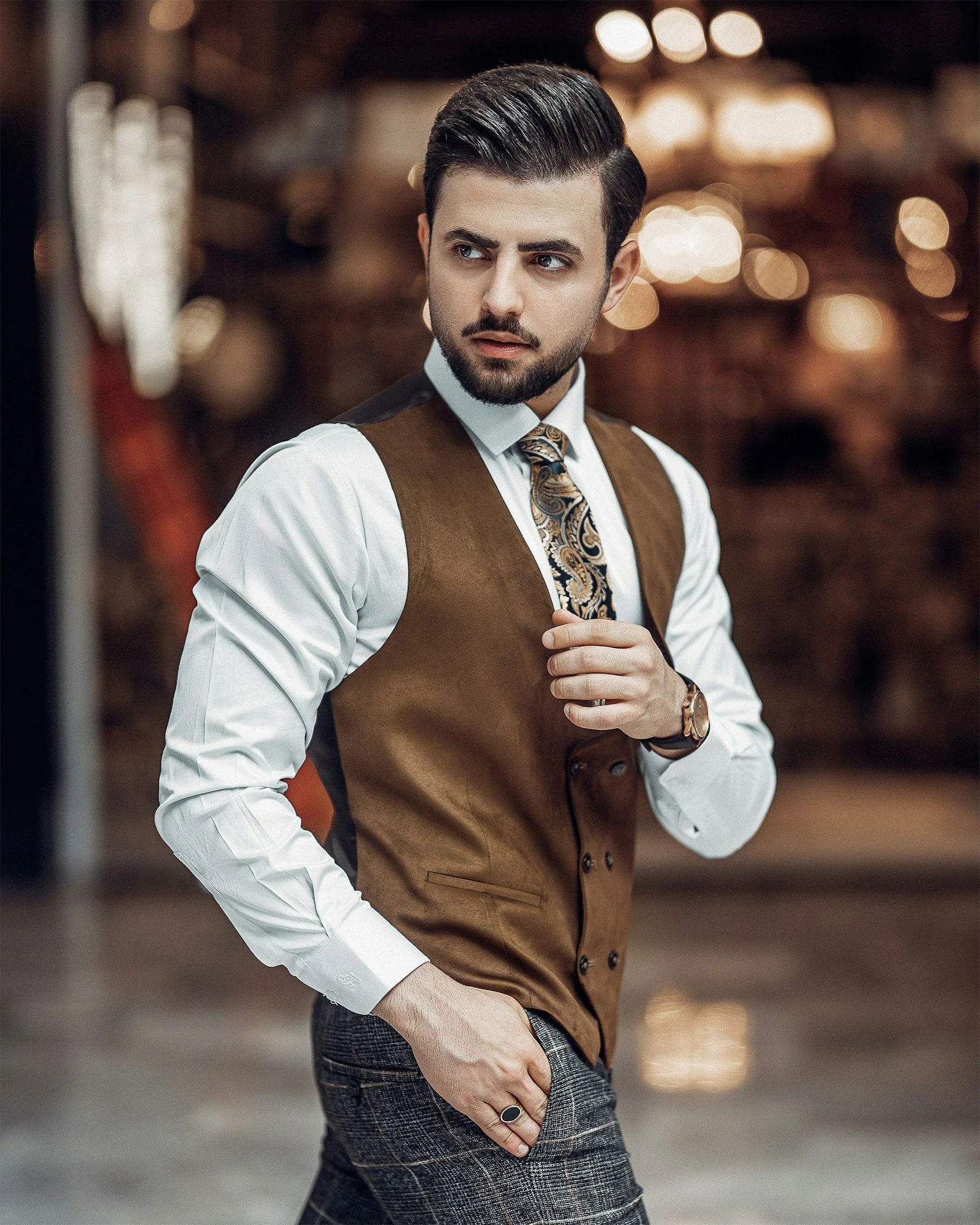 A man in a vest and tie is posing for a picture