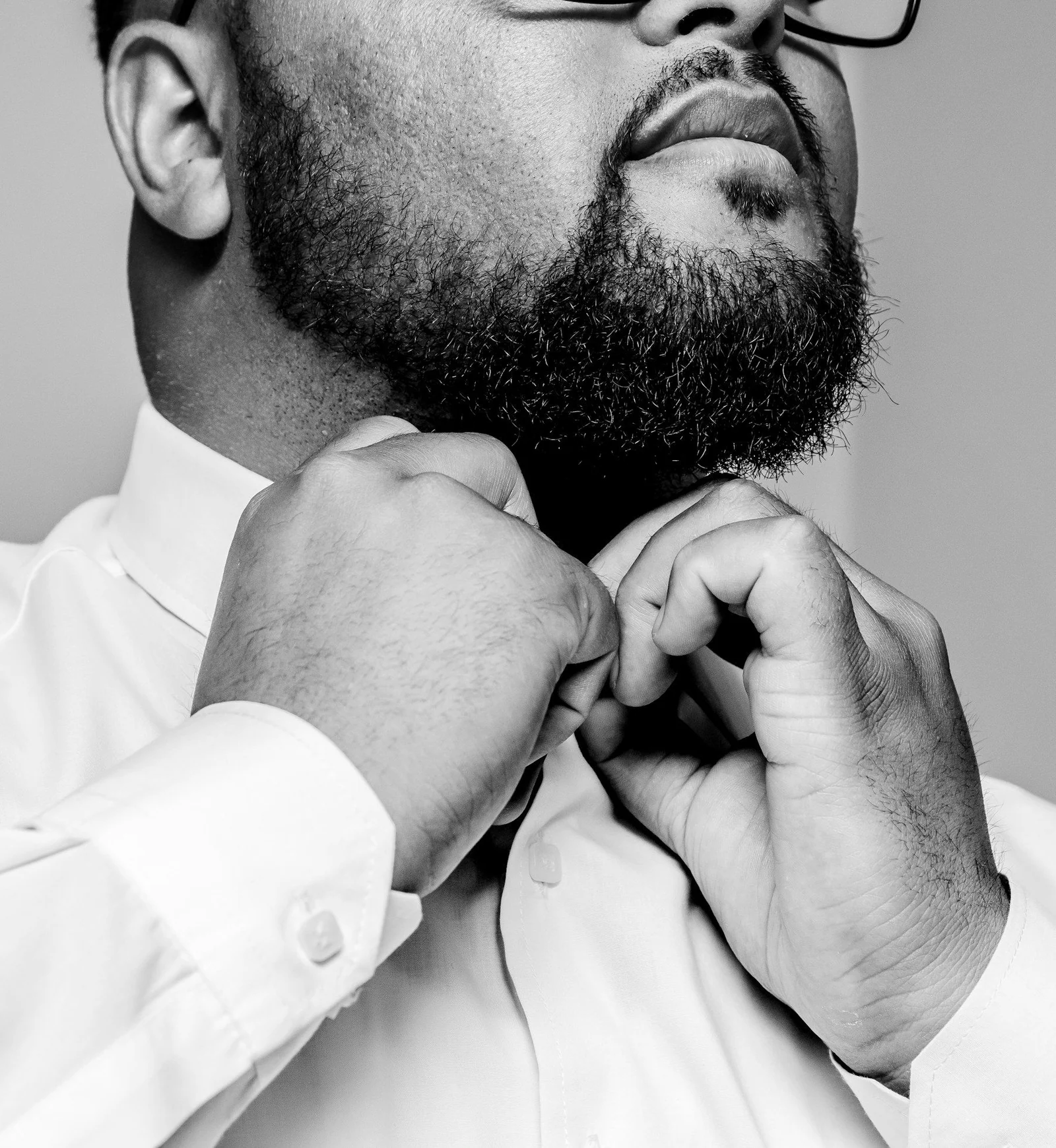 A black and white photo of a man adjusting his tie