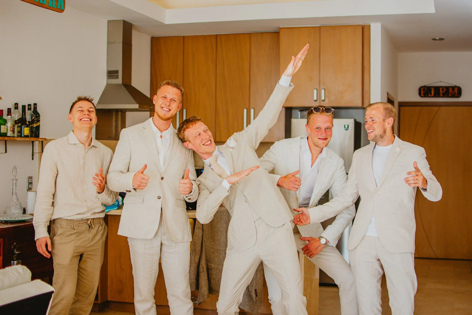 Groom and groomsmen in light suits celebrating