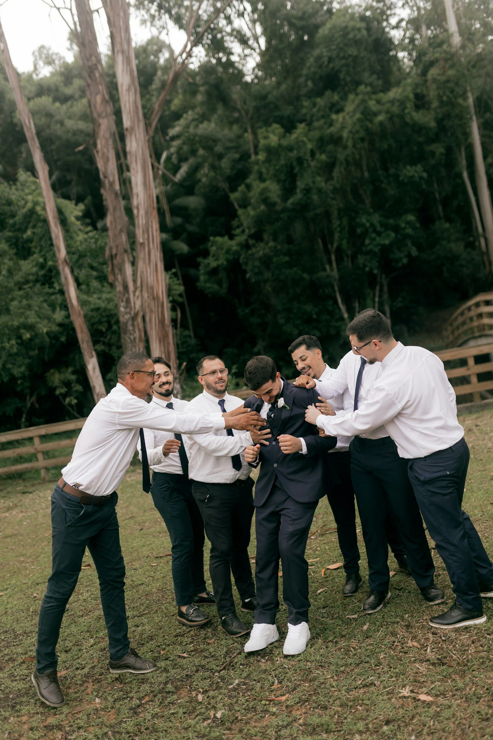 Groom and groomsmen playfully interact outdoors