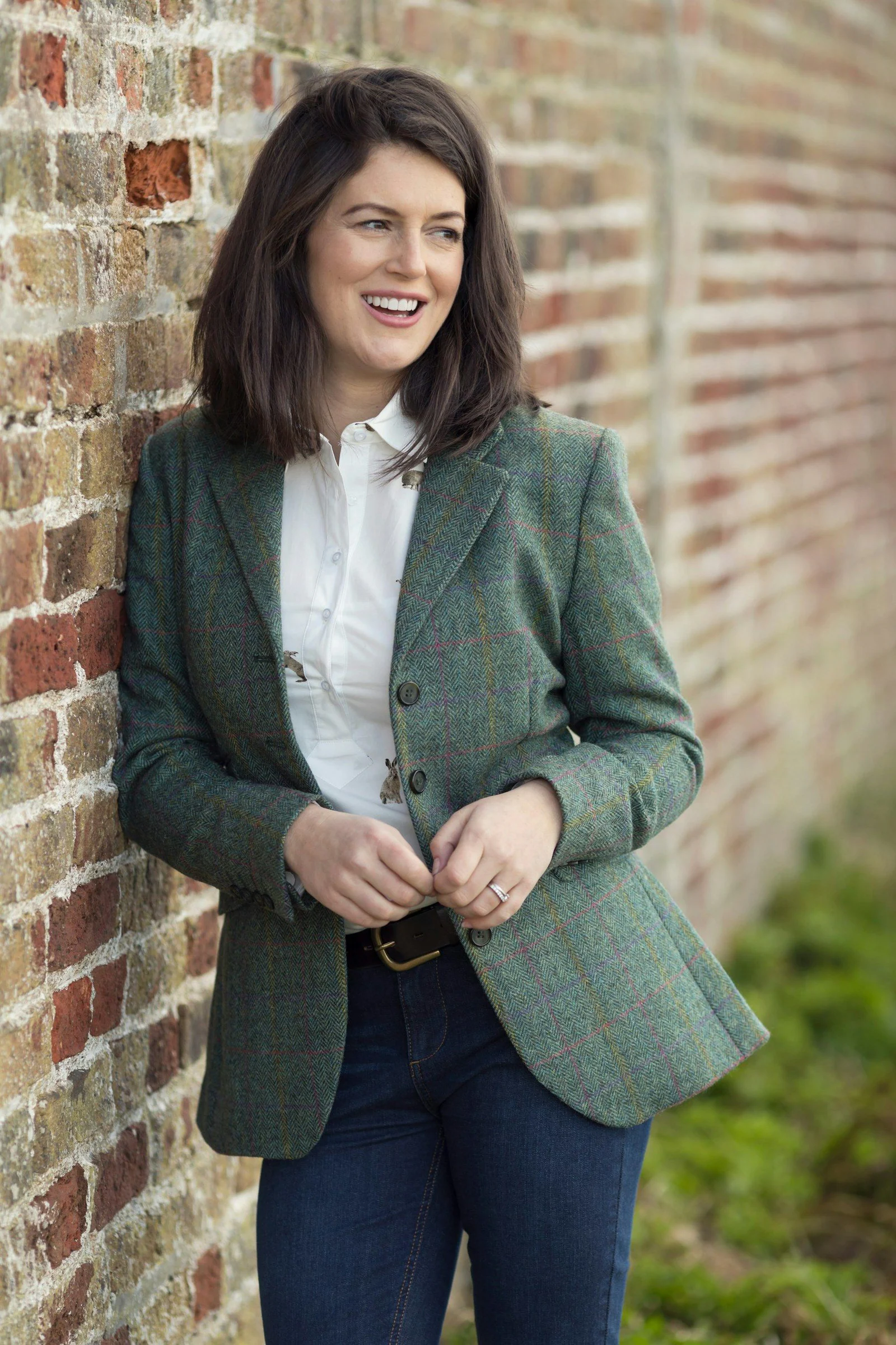 A woman leaning against a brick wall