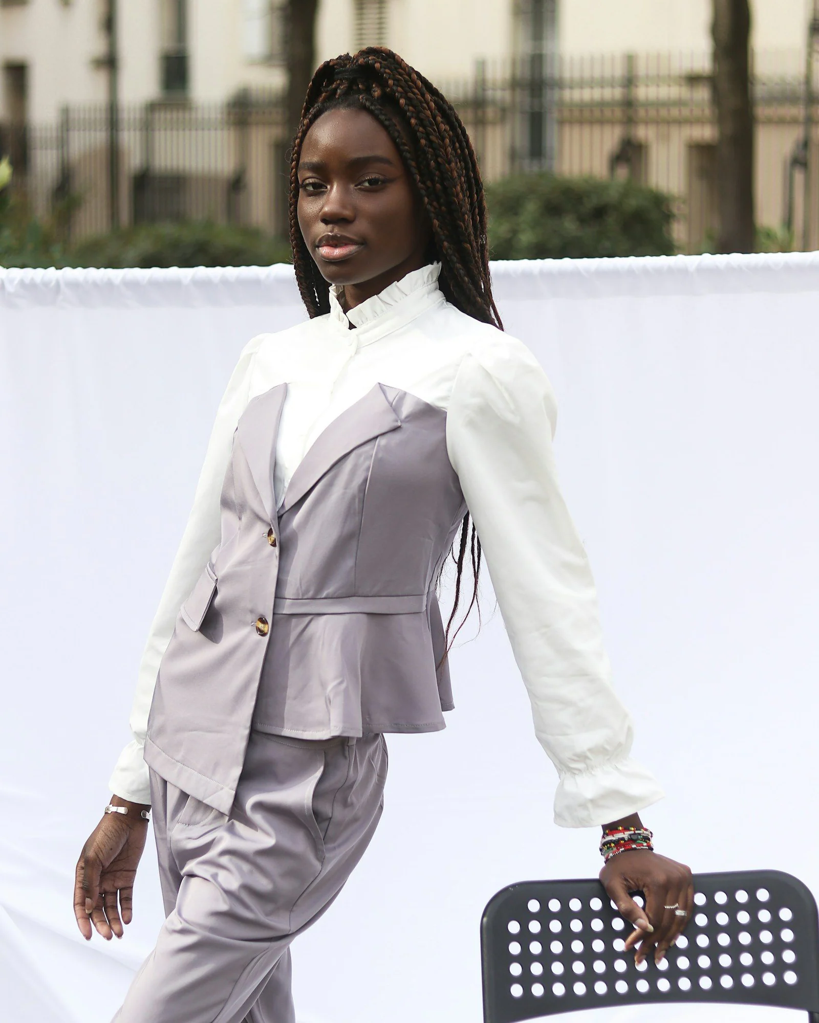 Woman in white blazer holding black skateboard