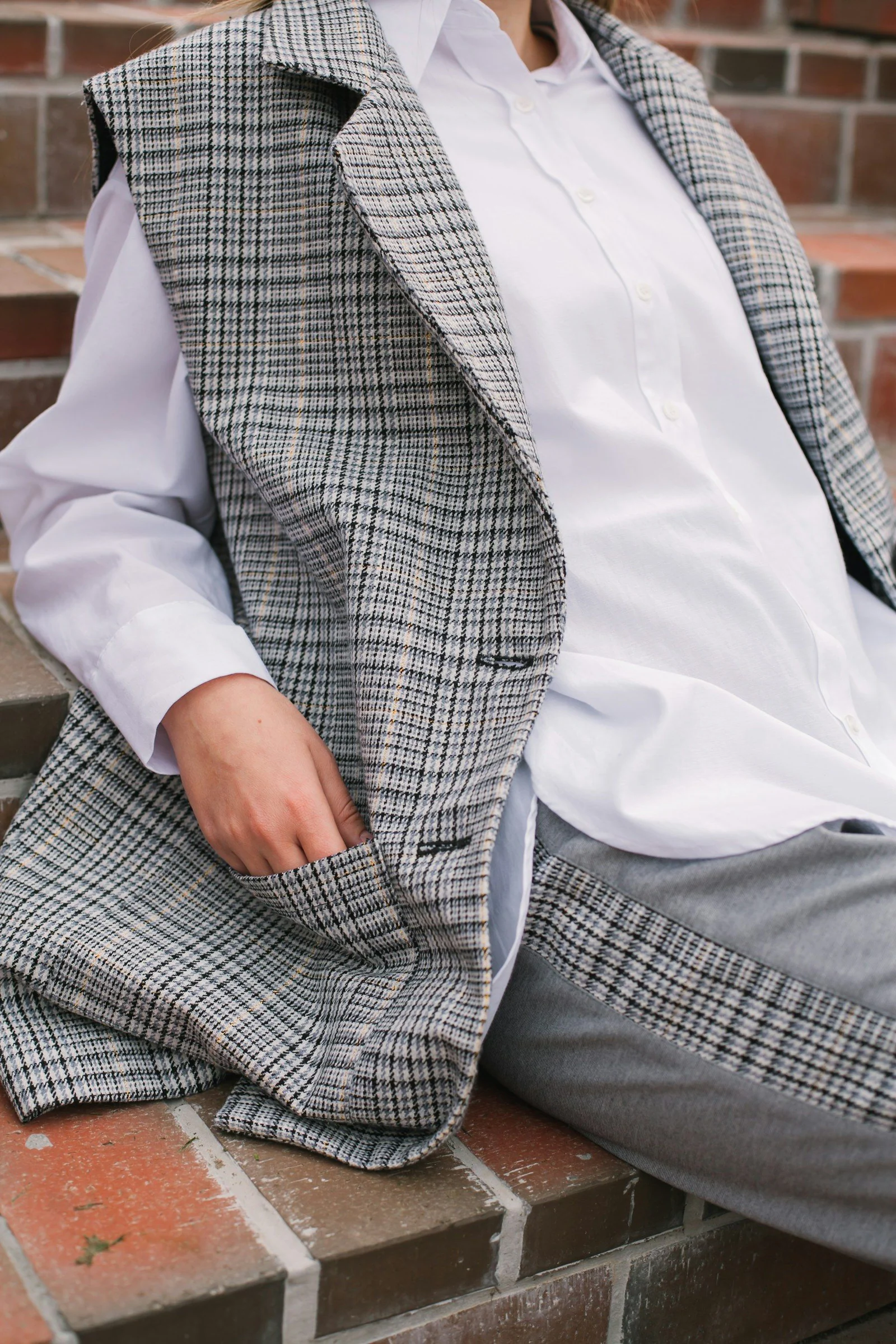 A man in a suit sitting on a brick wall