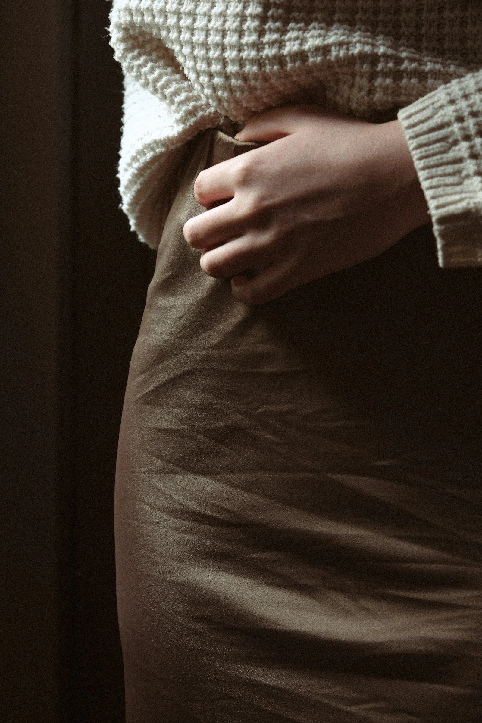 A woman in a skirt with her hands on her stomach
