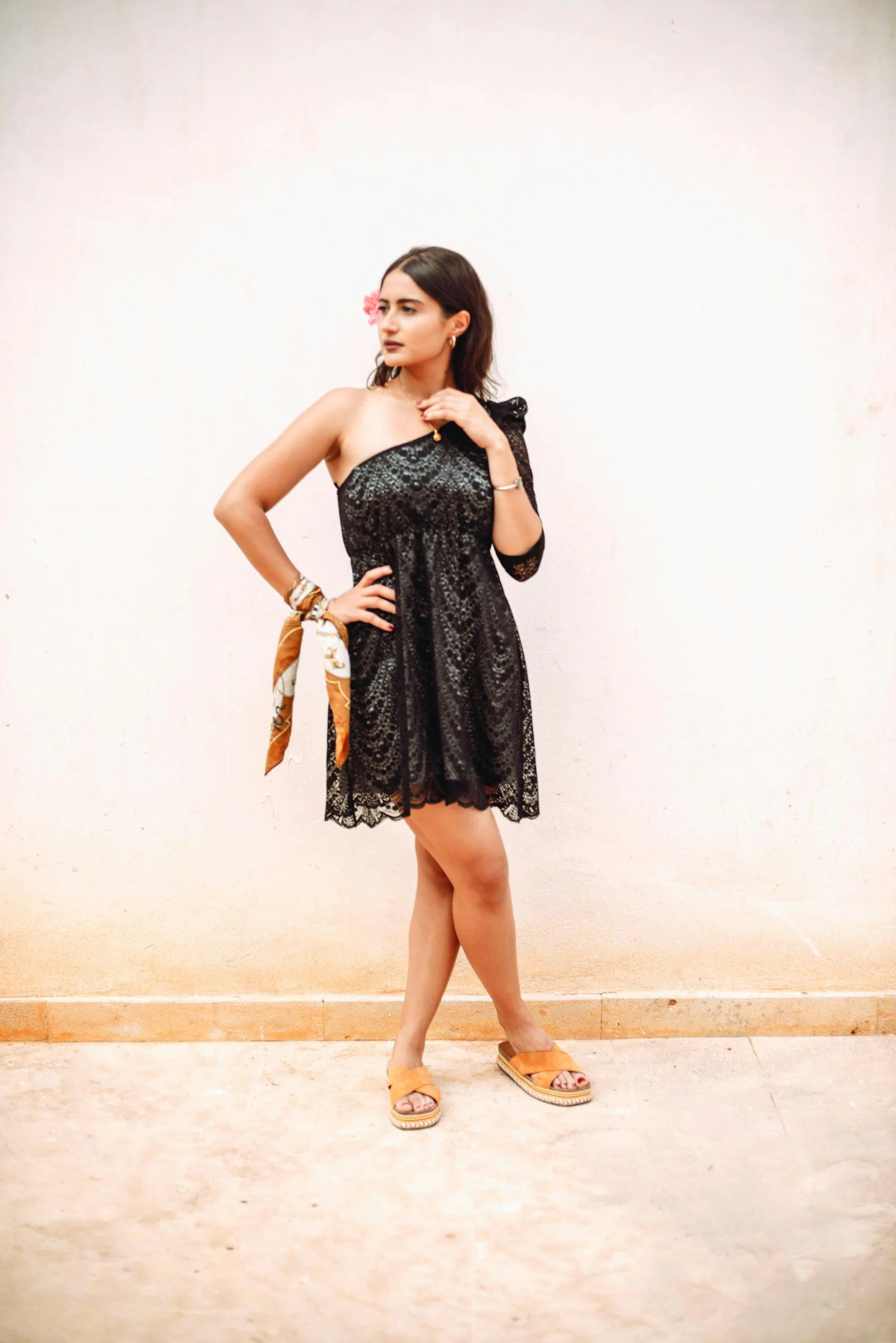 Woman in black and grey sleeveless dress standing beside white wall