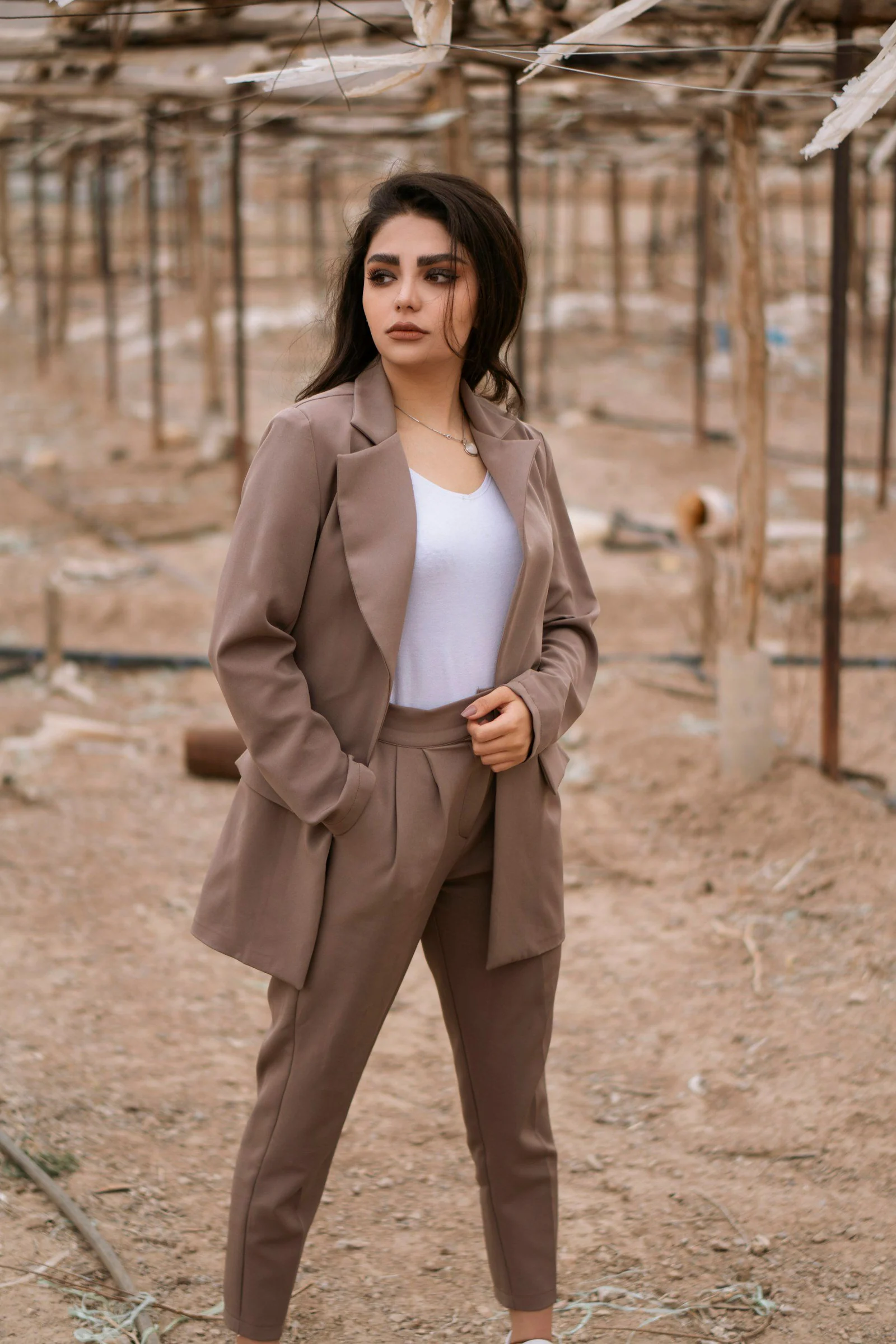 Woman in brown blazer standing on brown sand during daytime