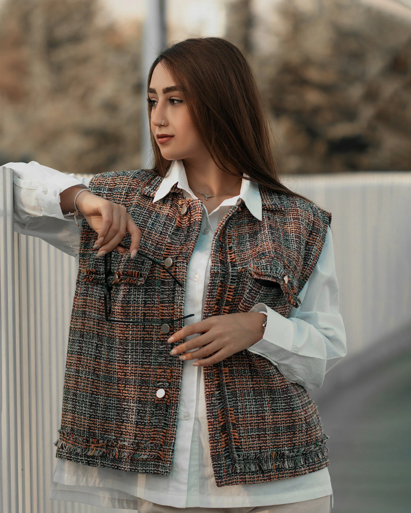 A woman pointing at something while standing next to a fence