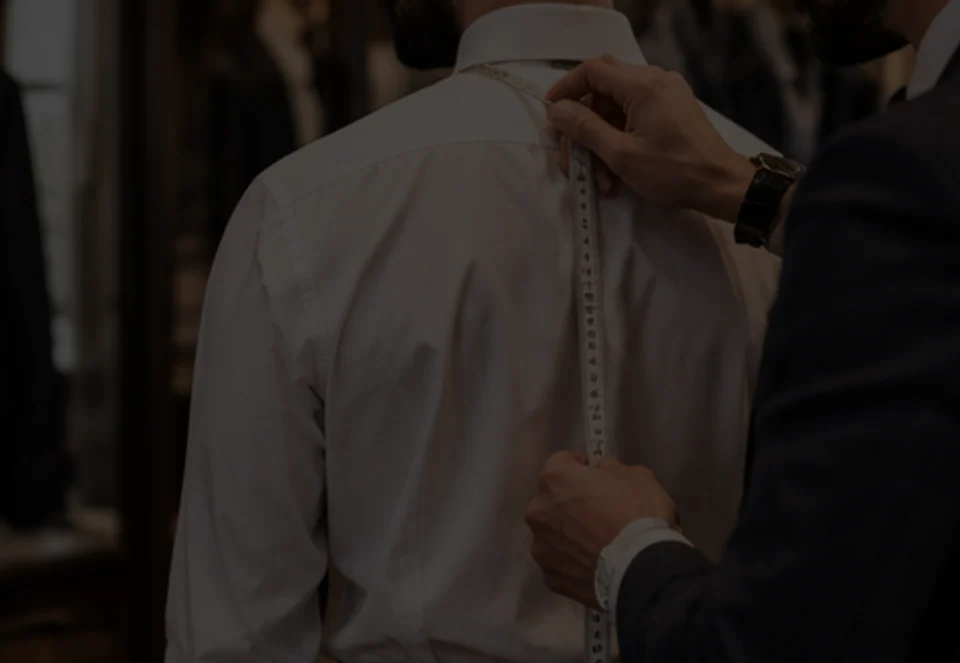 Tailor measuring a customer's back with a tape measure