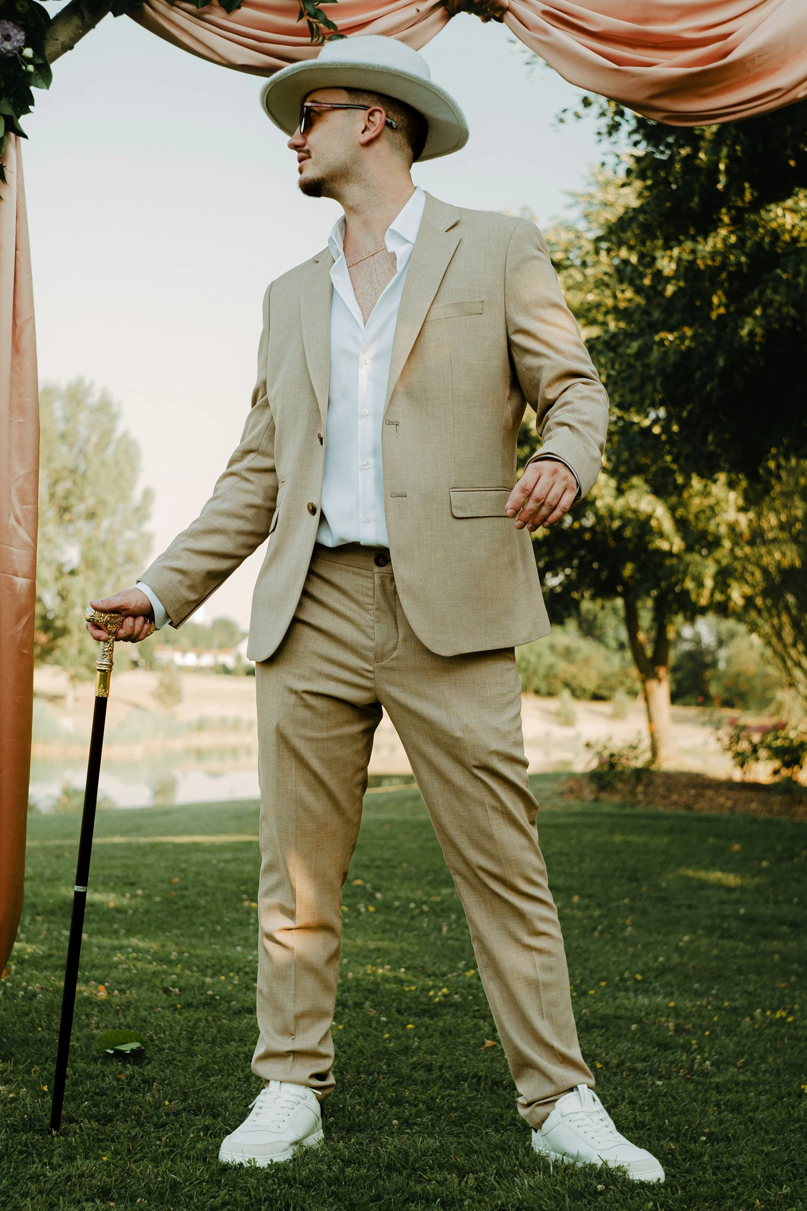 Cream casual suit with a straw hat and cane in a garden