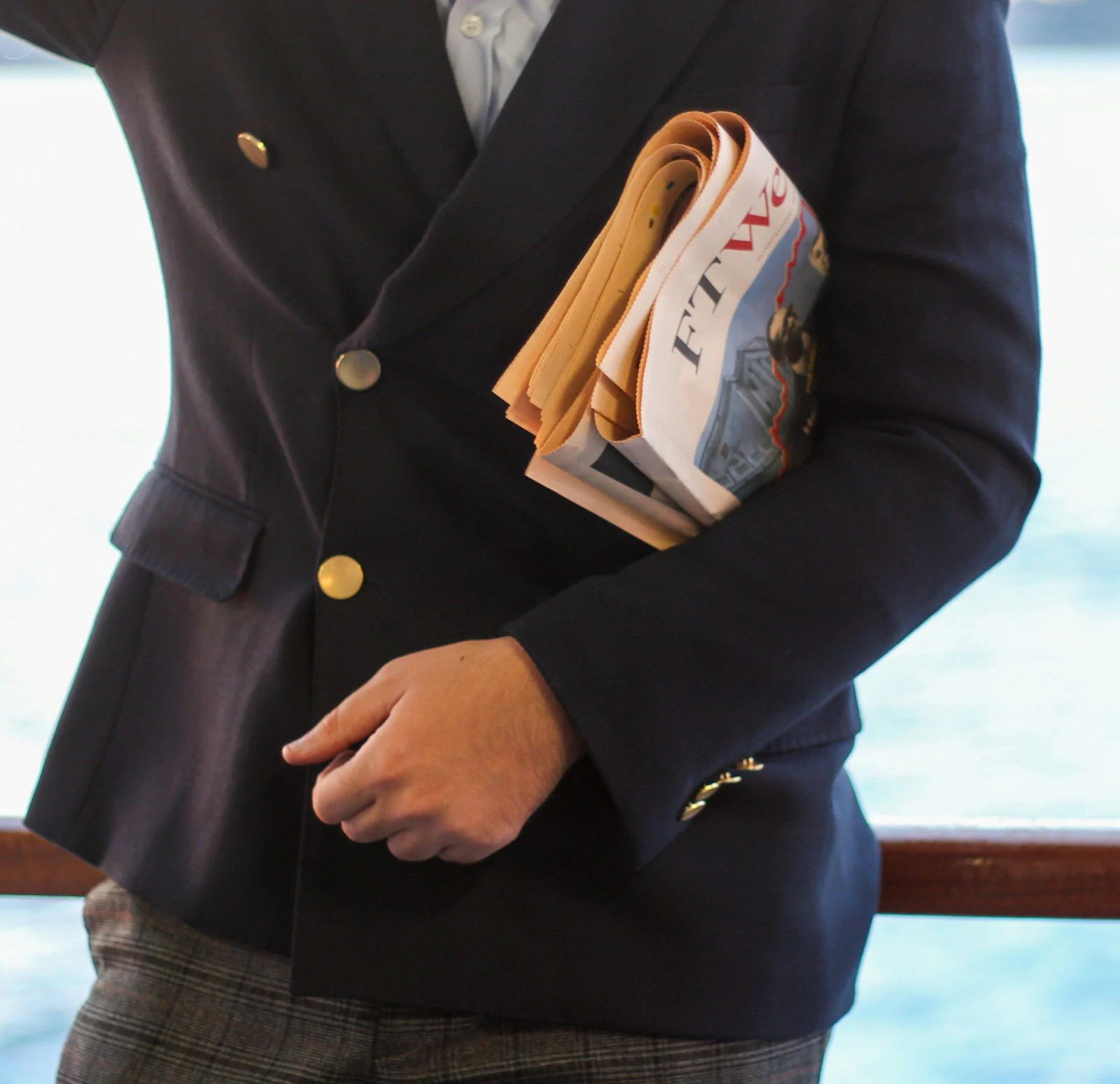 Navy double-breasted blazer with gold buttons and a newspaper