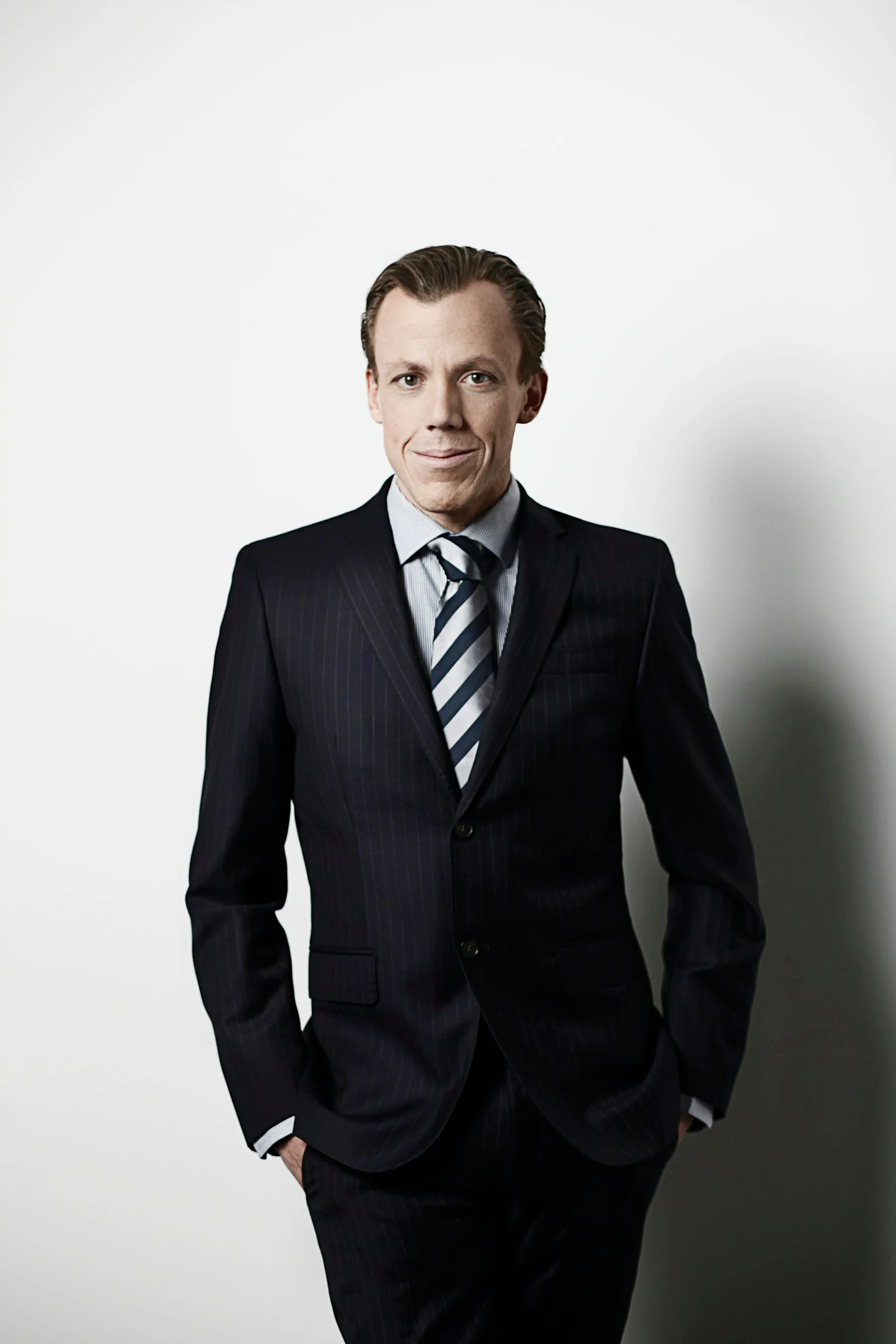 Man in a black formal suit and striped tie, studio portrait