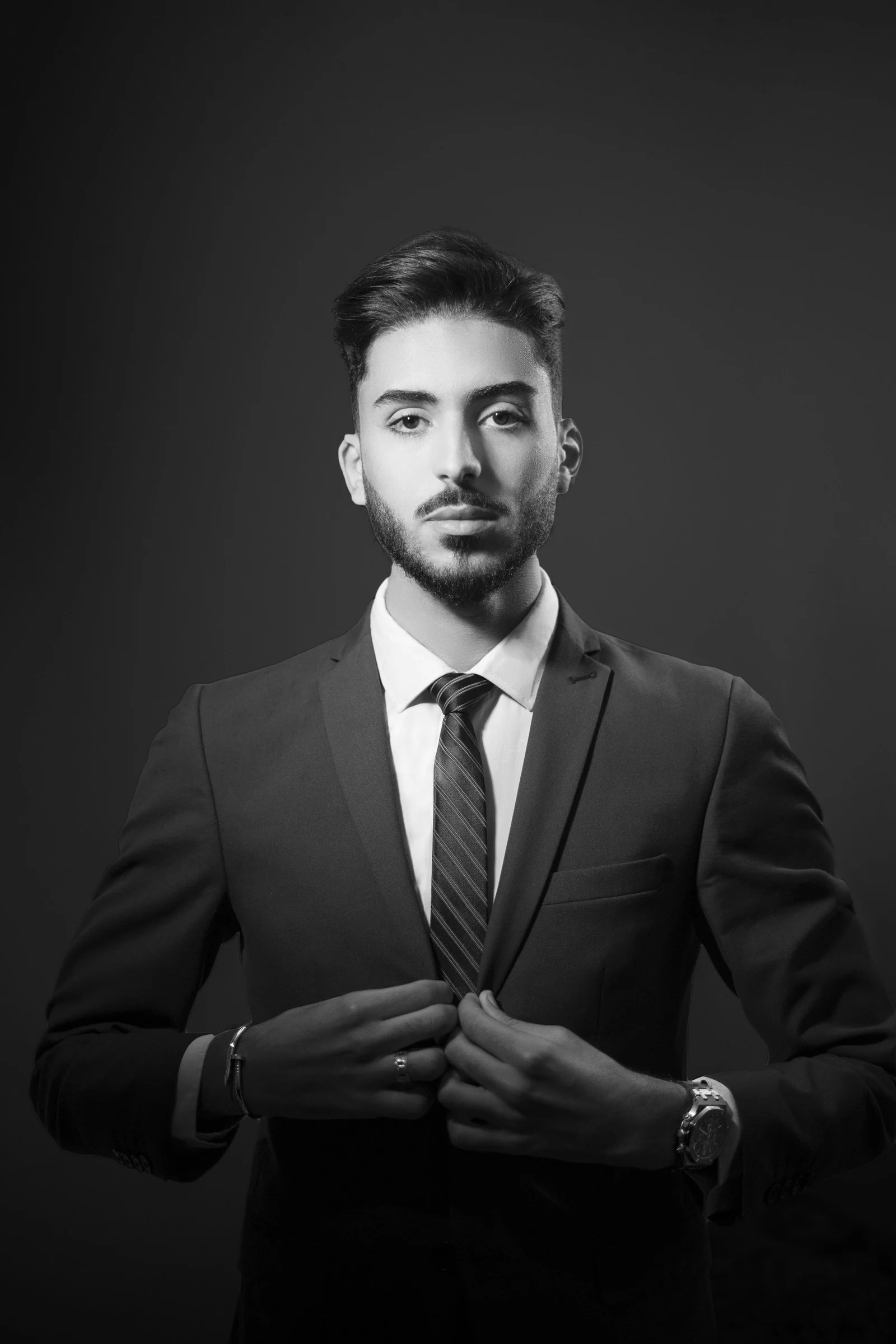 Man fastening a black formal suit, black and white