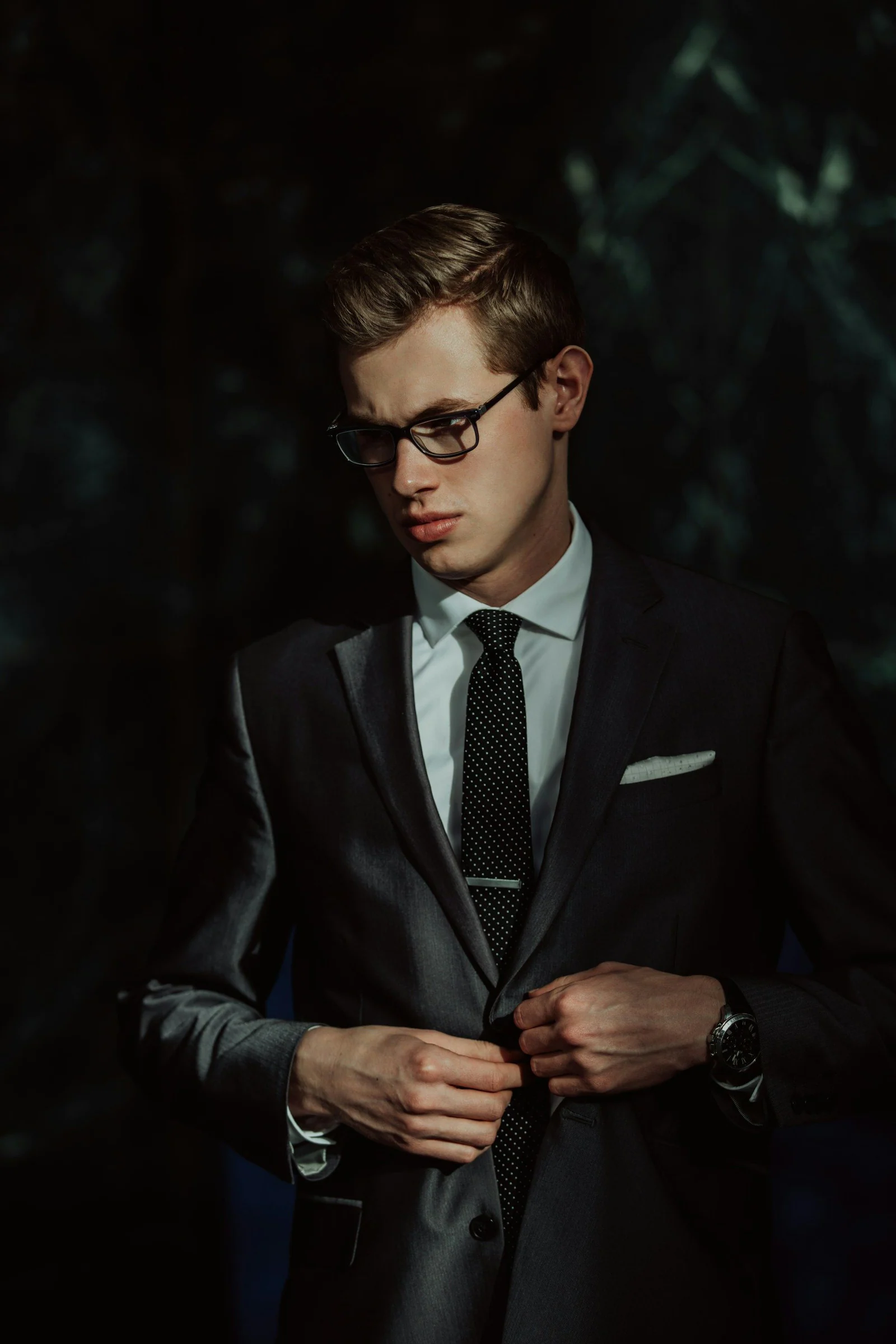 Man in a dark formal suit and tie in low light