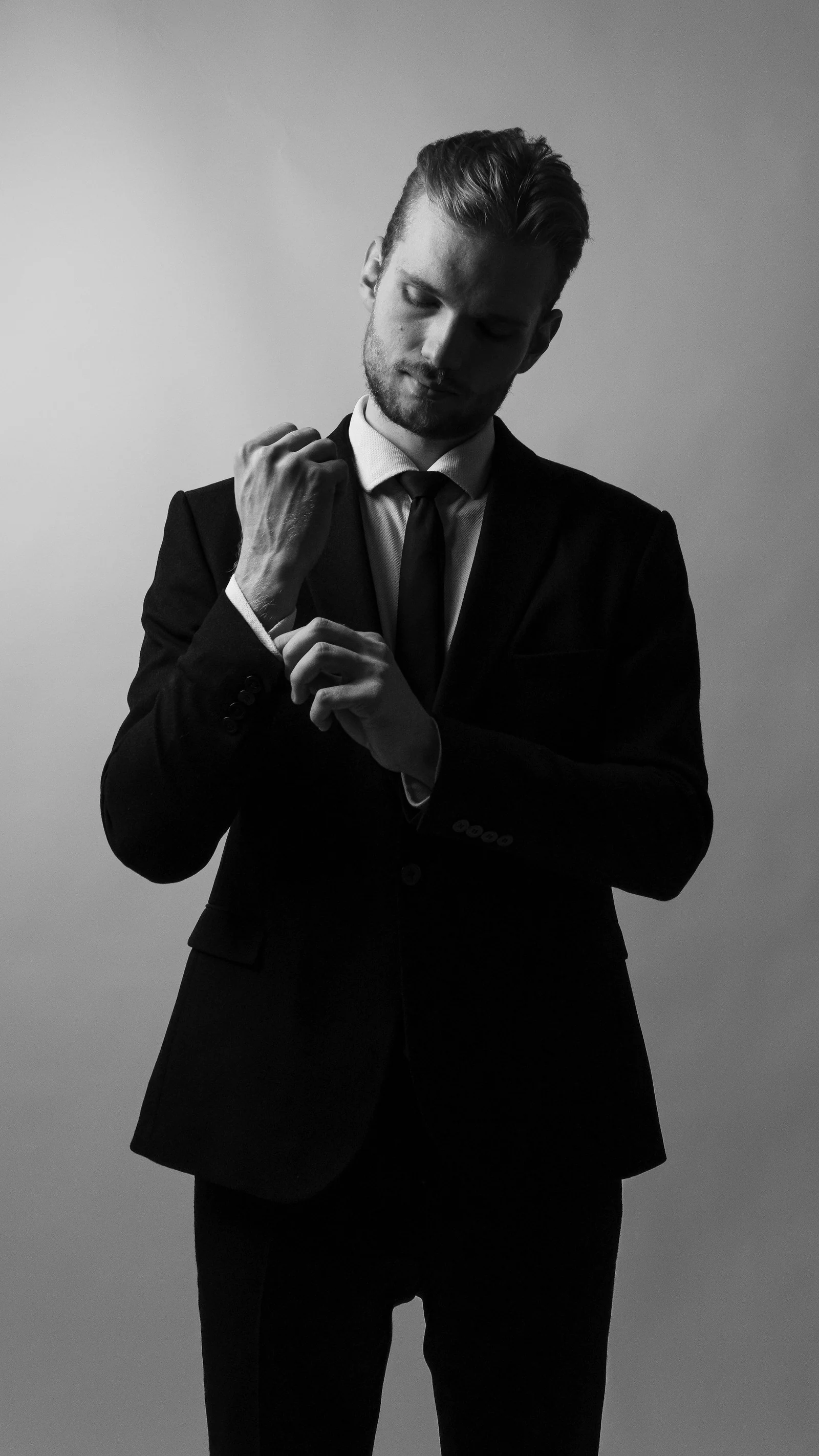 Black formal suit, adjusting a cufflink, black and white