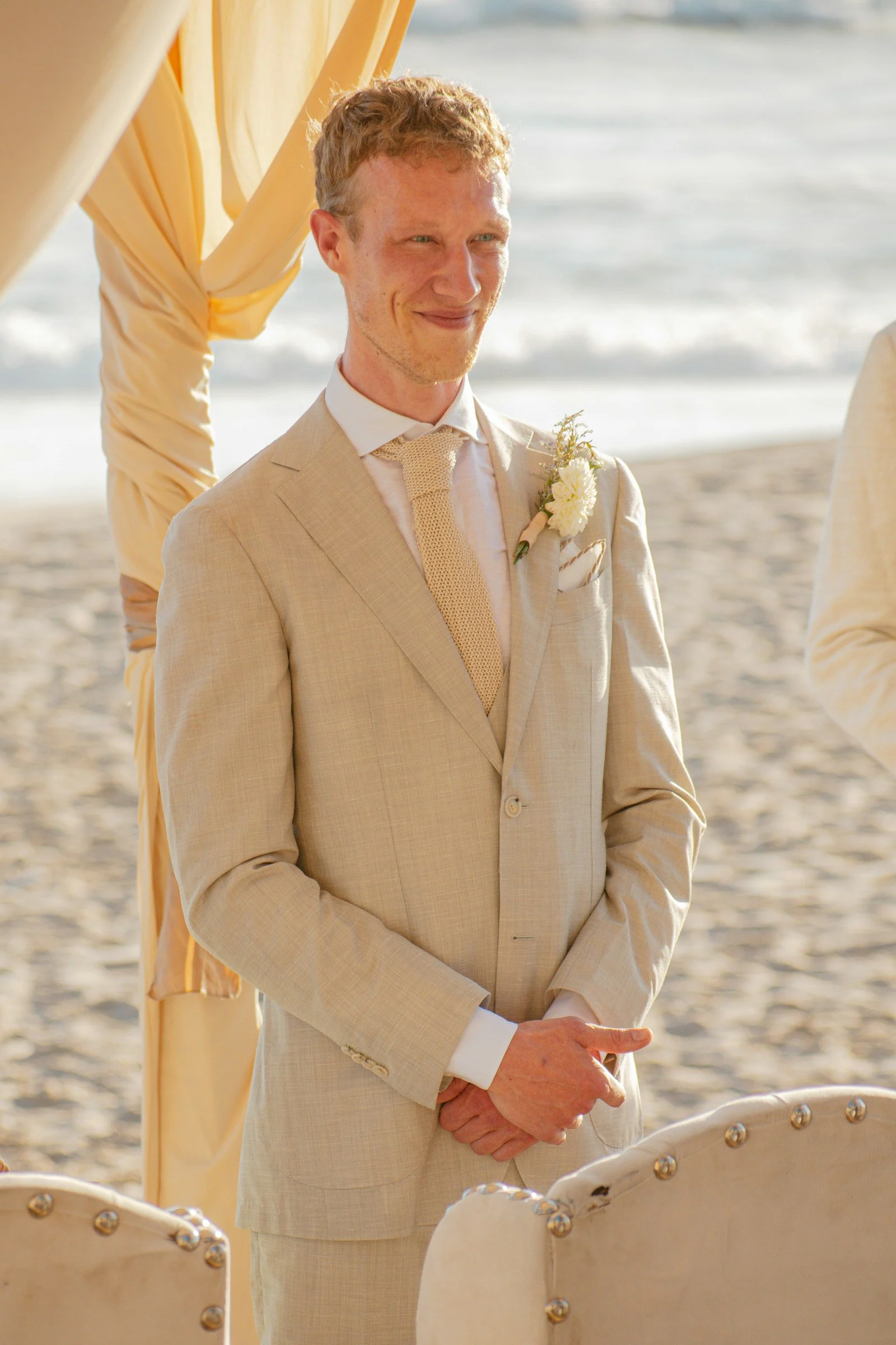 Groom in a sand linen suit at a beach wedding