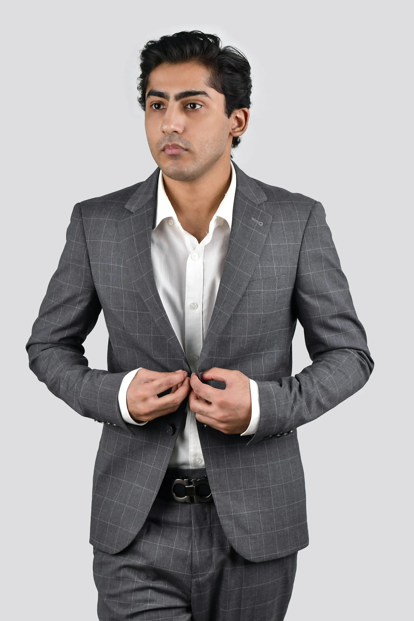 Man in a grey check two-piece suit, buttoning the jacket